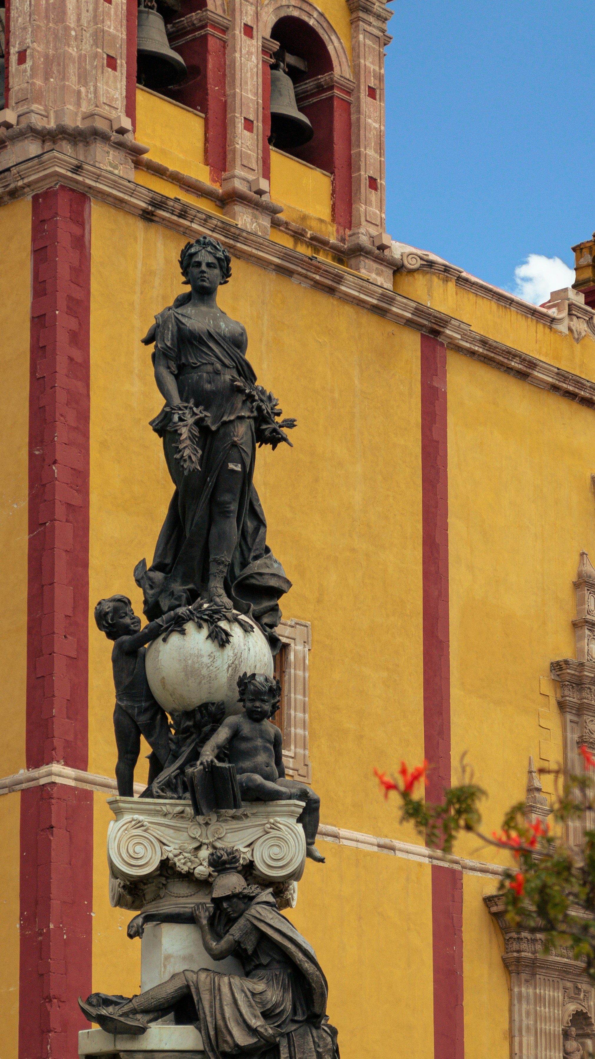 A statue is in front of a yellow building