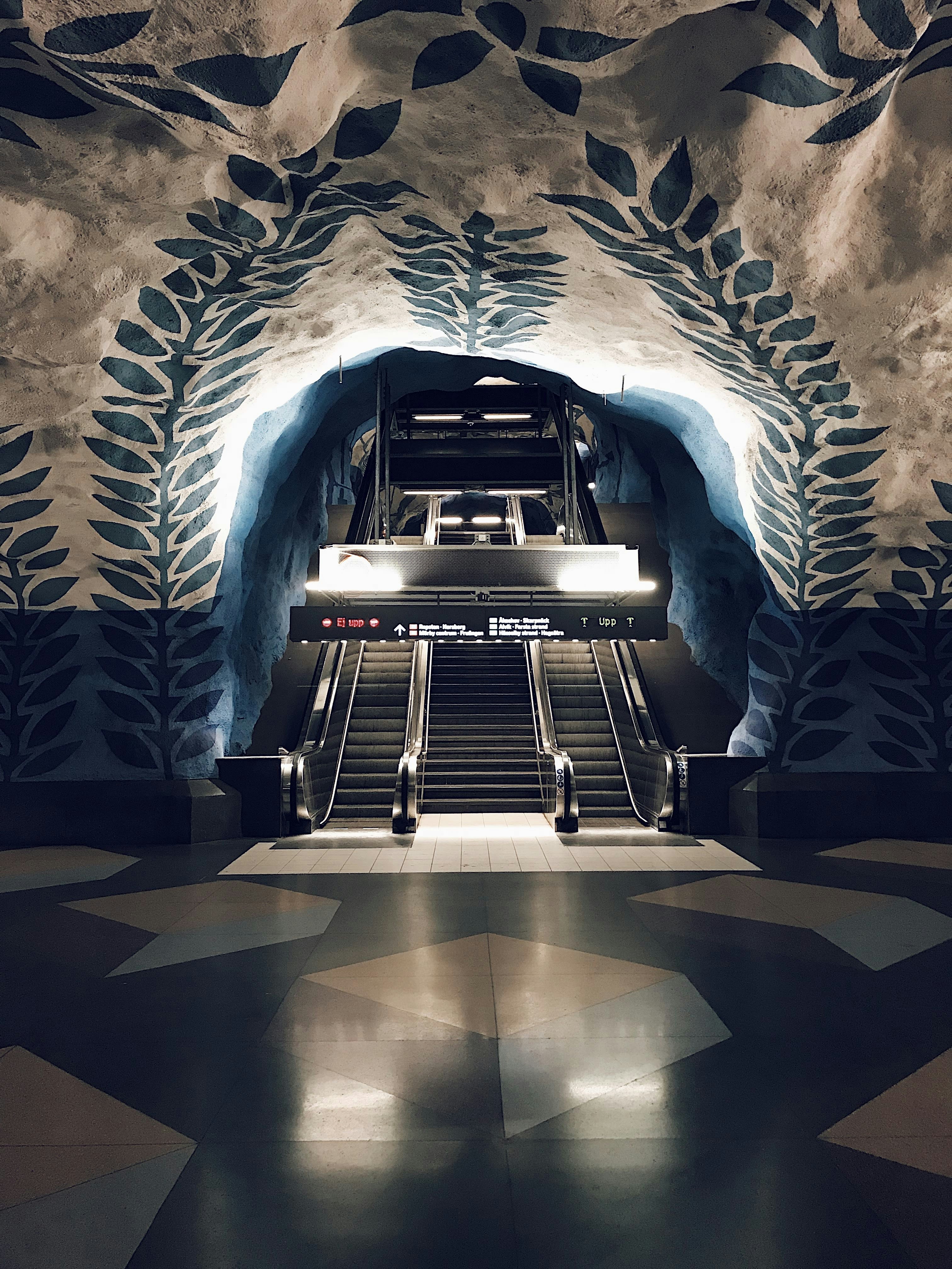 An escalator in a building with a mural on the wall
