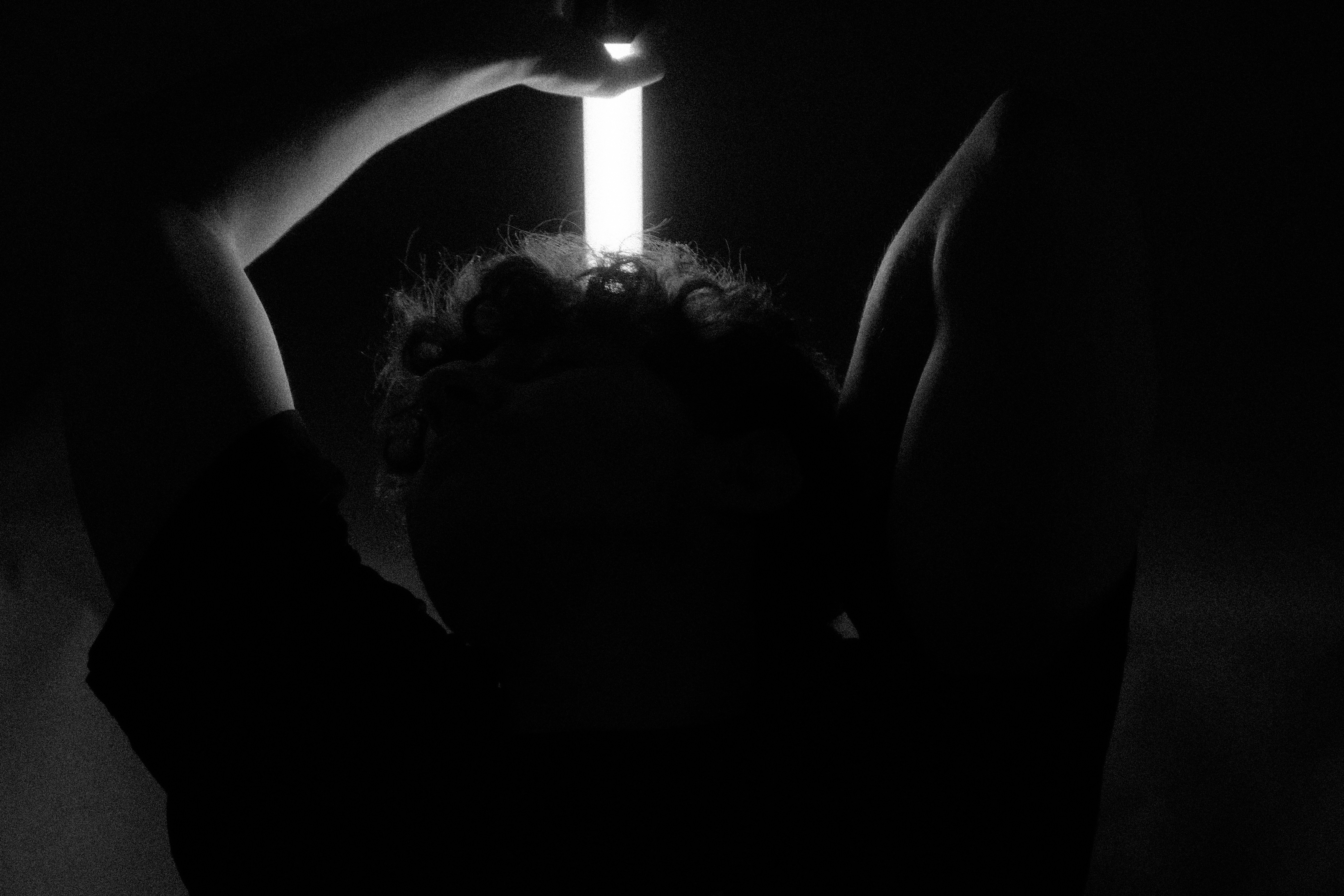 A person holding a lit candle in the dark