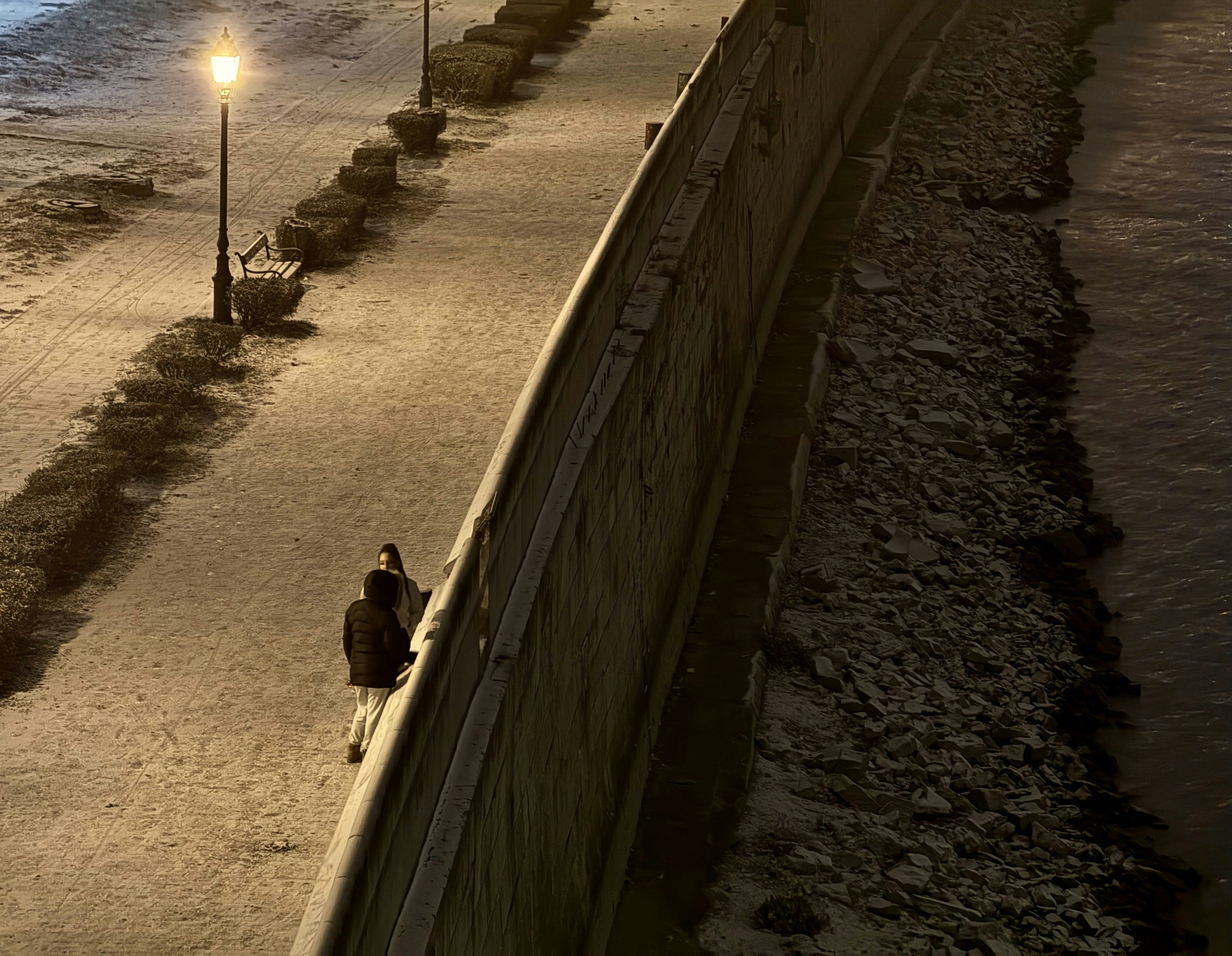 A couple of people walking down a sidewalk next to the ocean