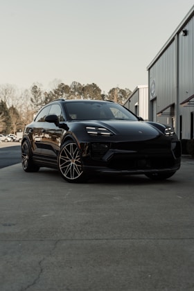 A black porsche suv parked in front of a building