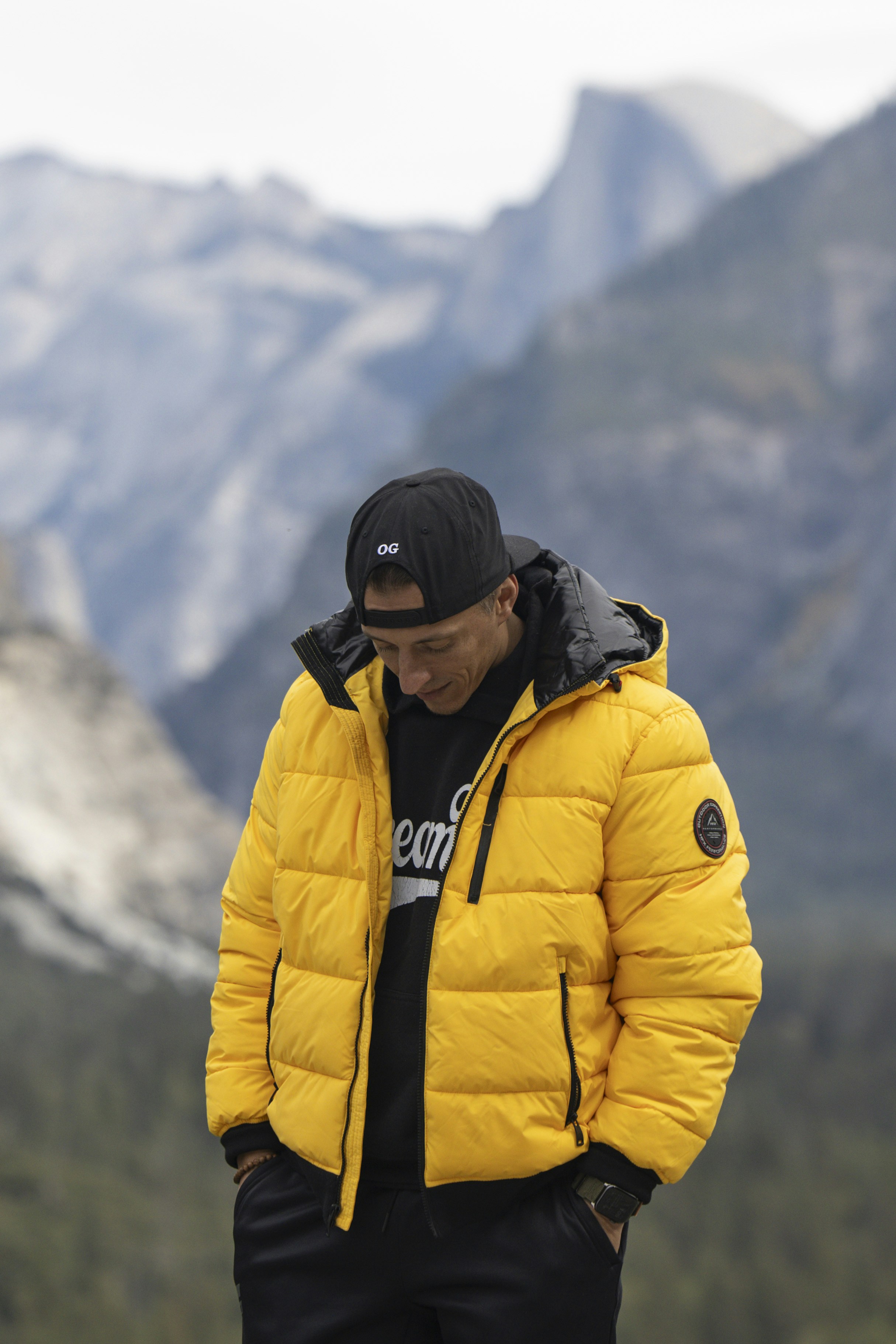 A man in a yellow jacket standing on a mountain