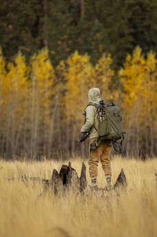 A man with a backpack is standing in a field