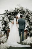 A bride and groom standing under a floral arch