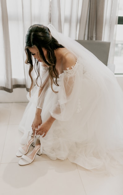 A woman in a wedding dress tying her shoes