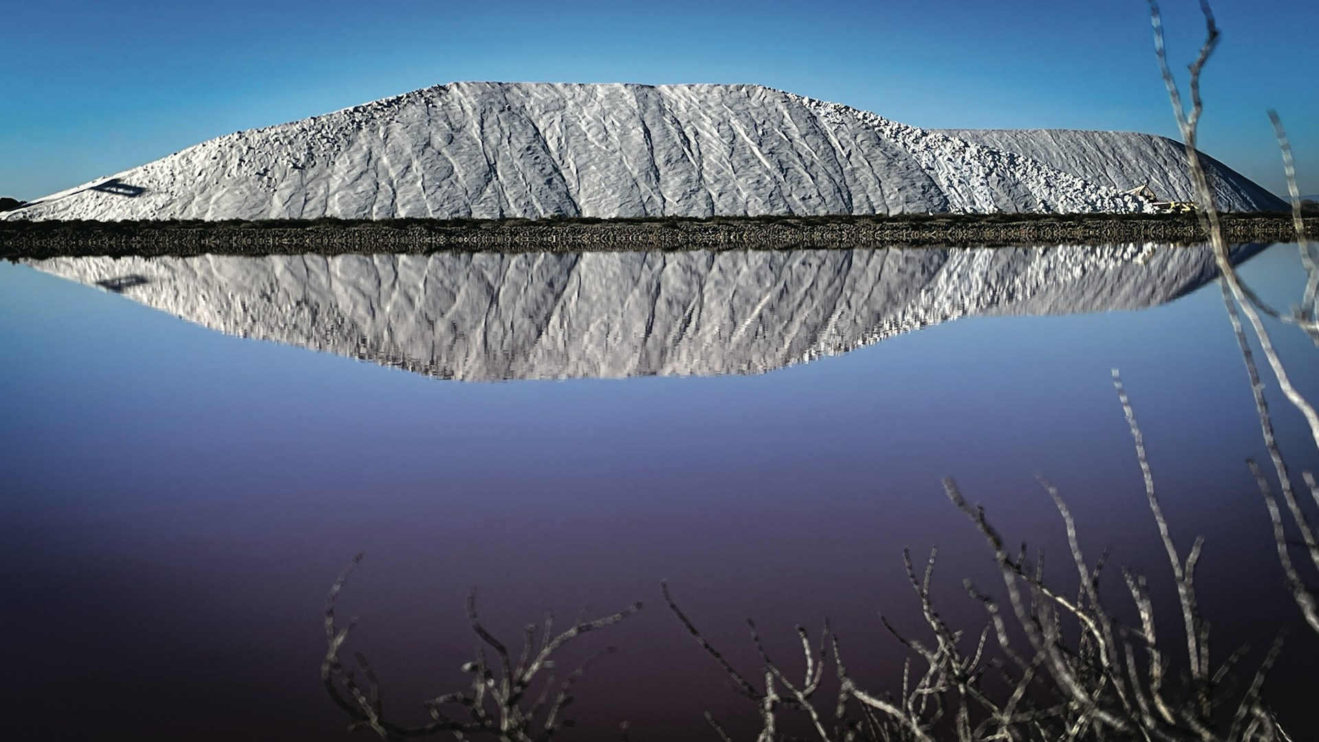 A snow covered mountain reflected in a still body of water