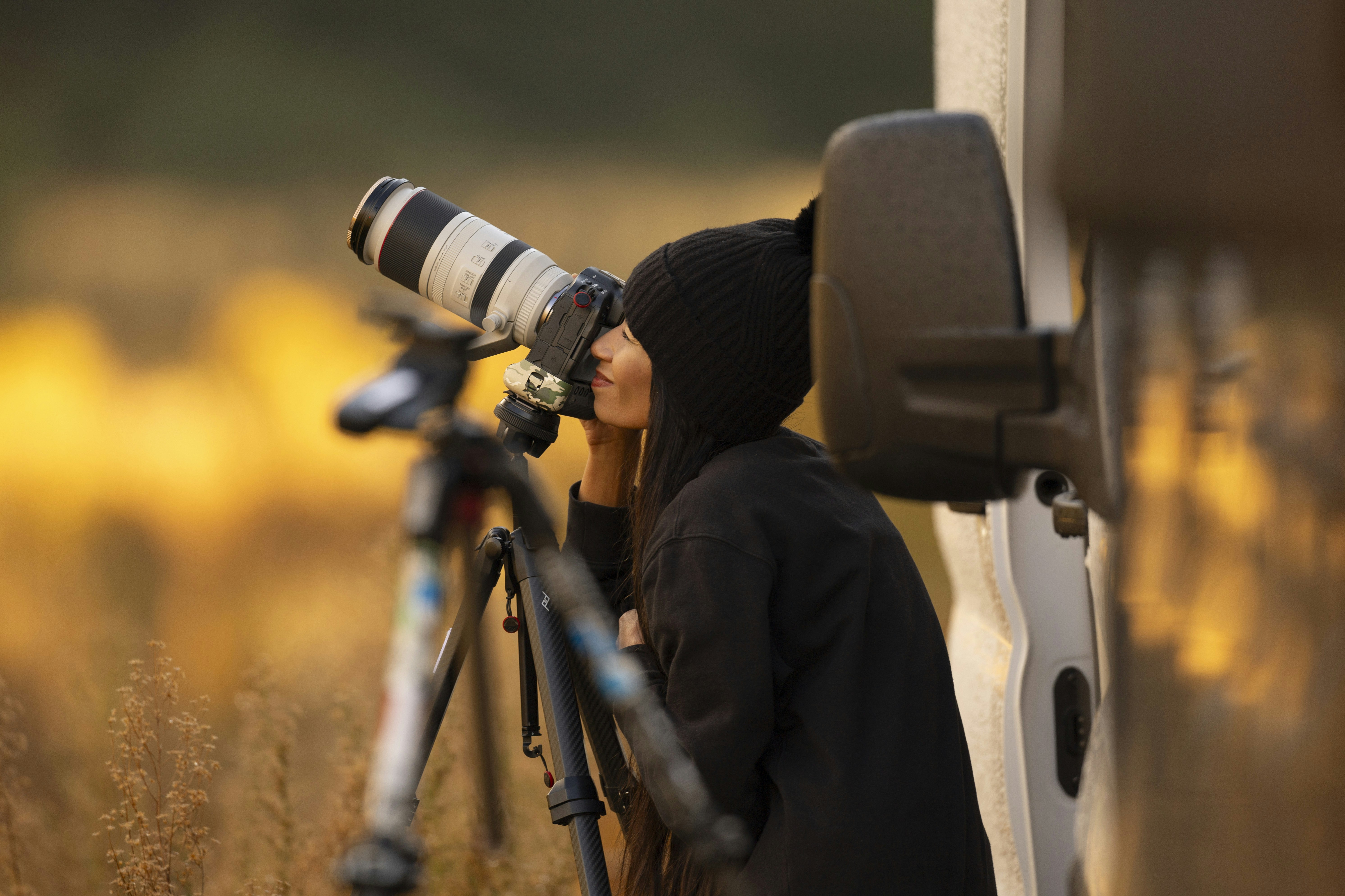 A woman with a camera and a tripod standing next to a van