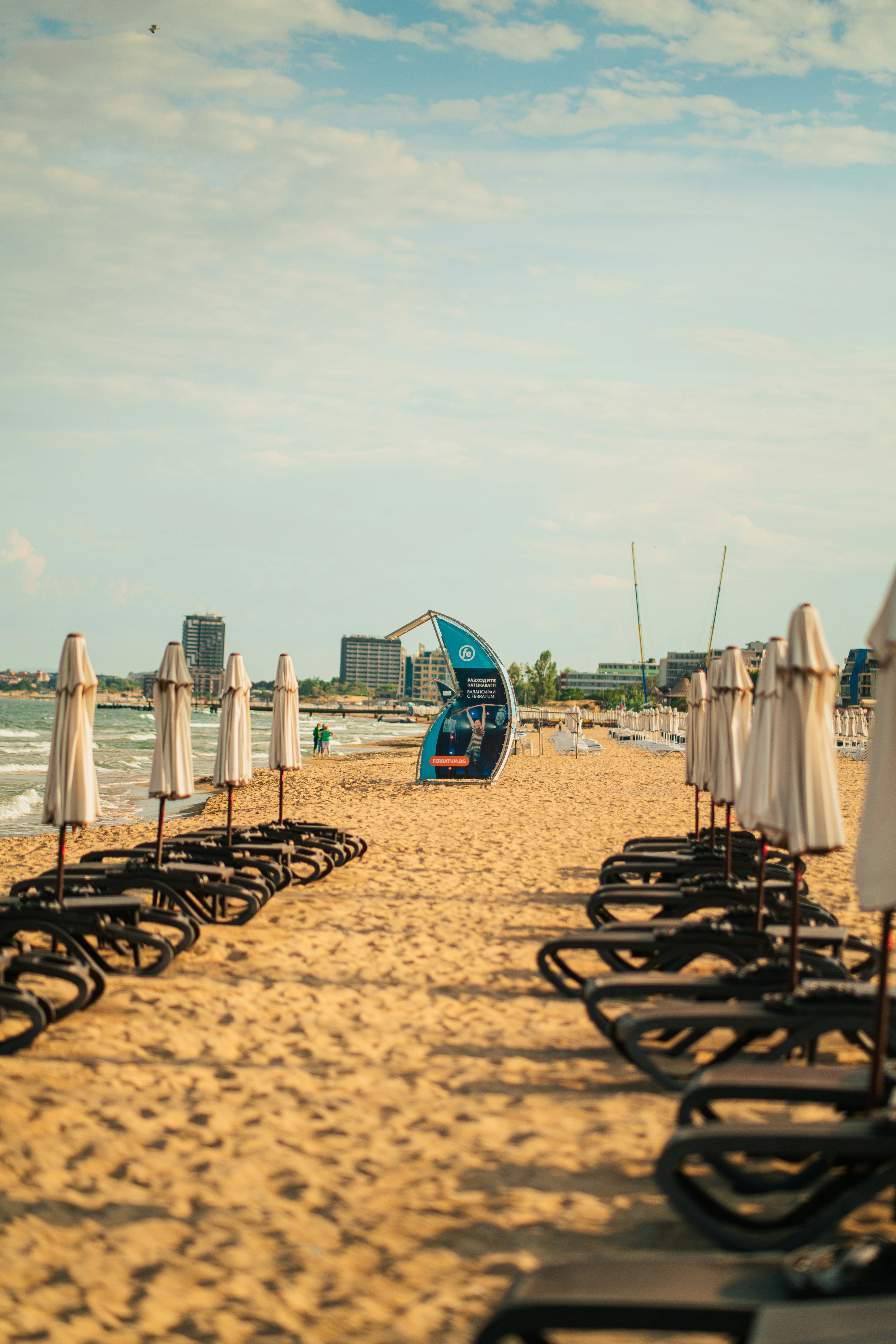 Una fila de sillas de playa sentadas en la parte superior de una playa de arena