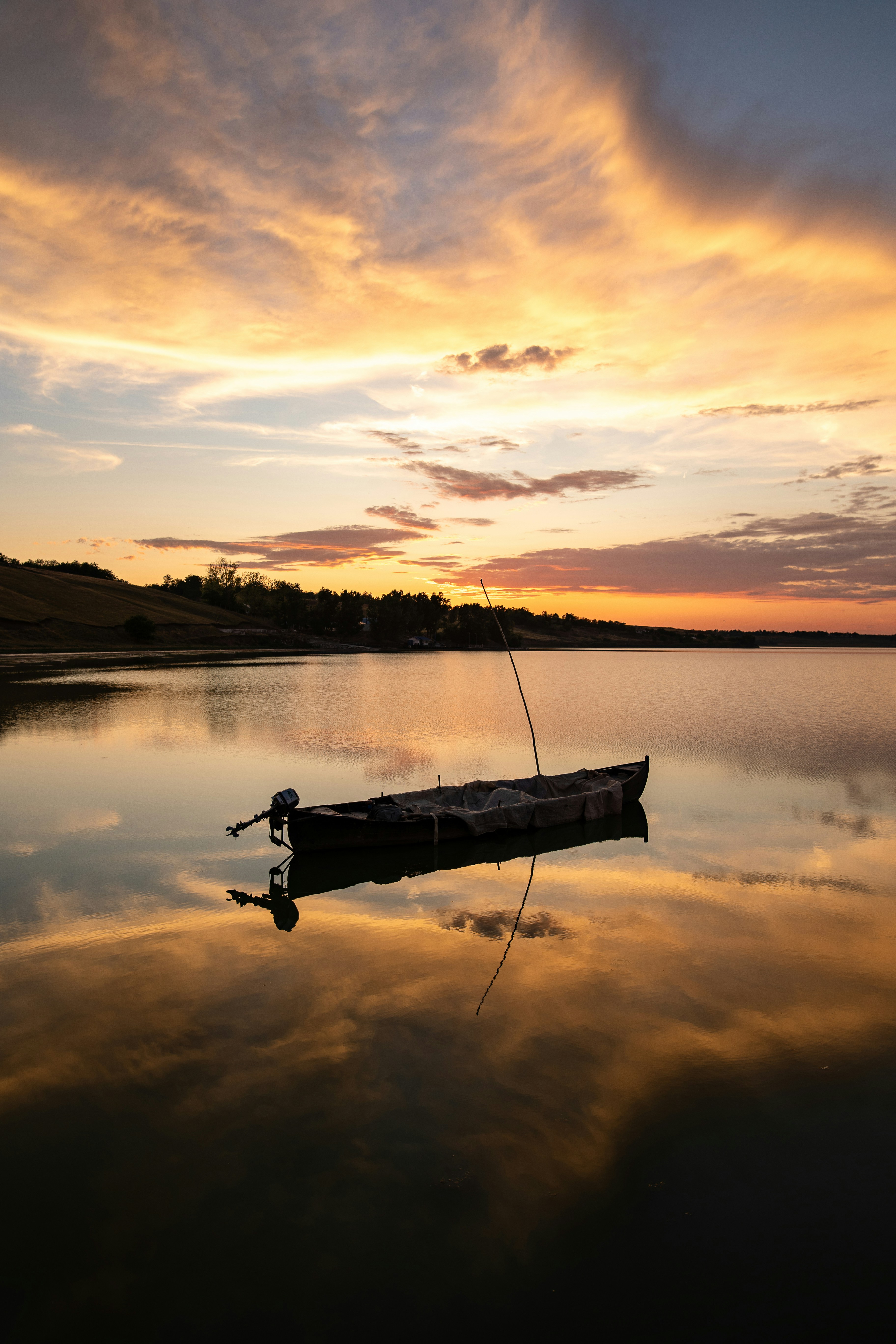A boat floating on top of a lake under a cloudy sky