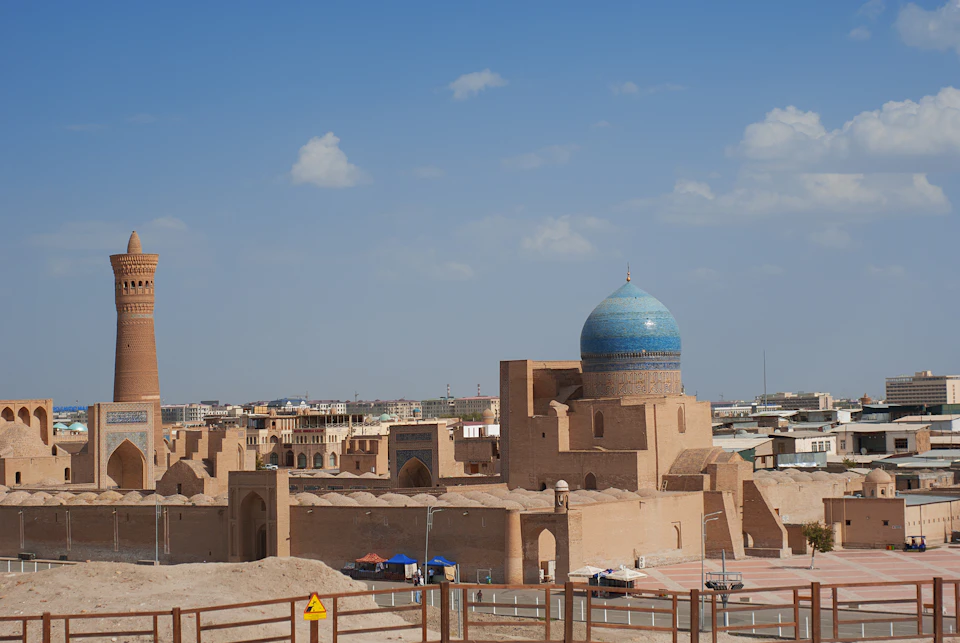 Large blue dome-shaped building with green roof and tower stands amidst city structures