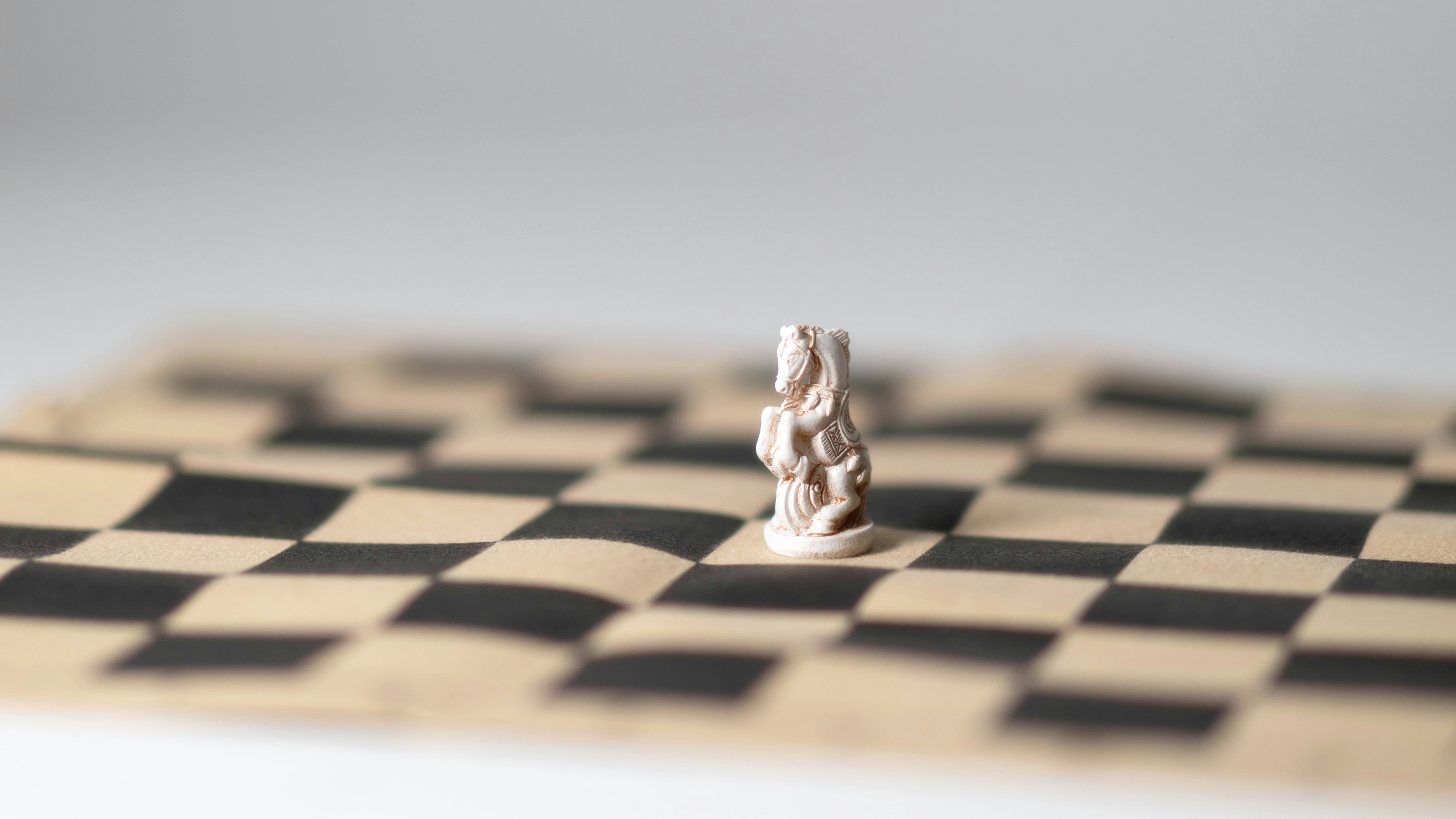 A tiny figurine is sitting on a chess board