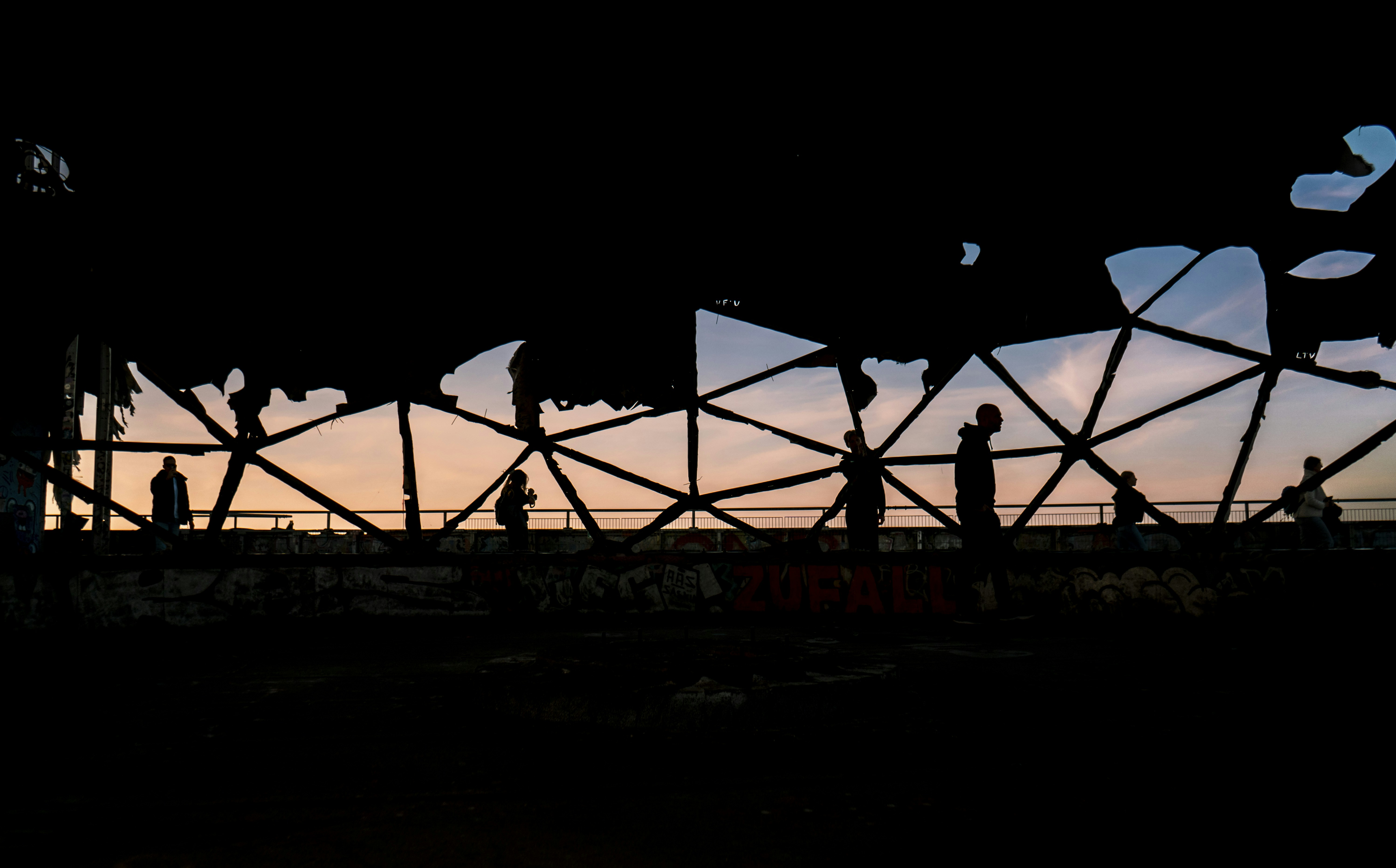 A silhouette of people standing on a bridge at sunset