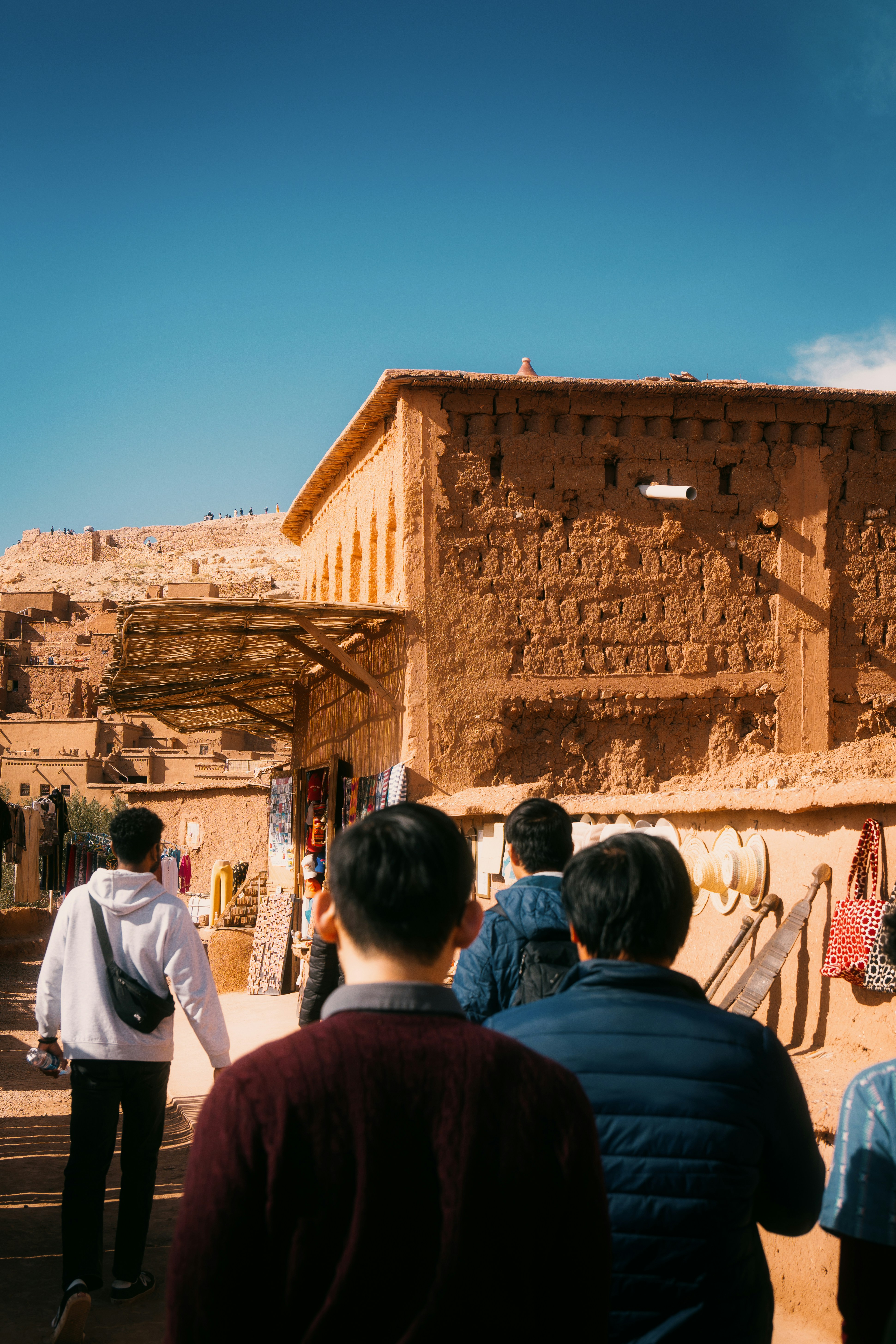 Visitors walk past market stalls in an ancient earthen village.