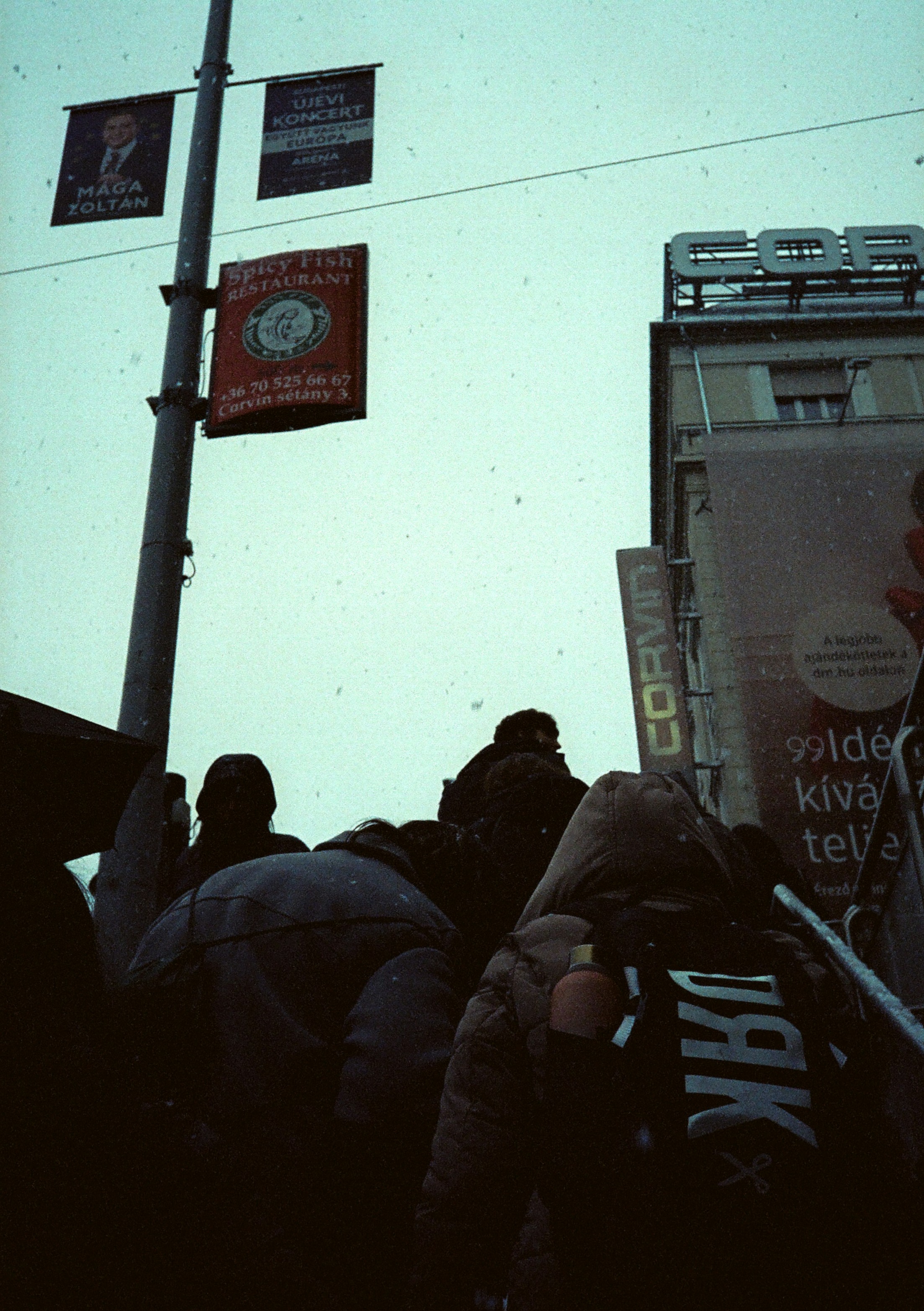 A group of people walking down a street next to a tall building photo ...