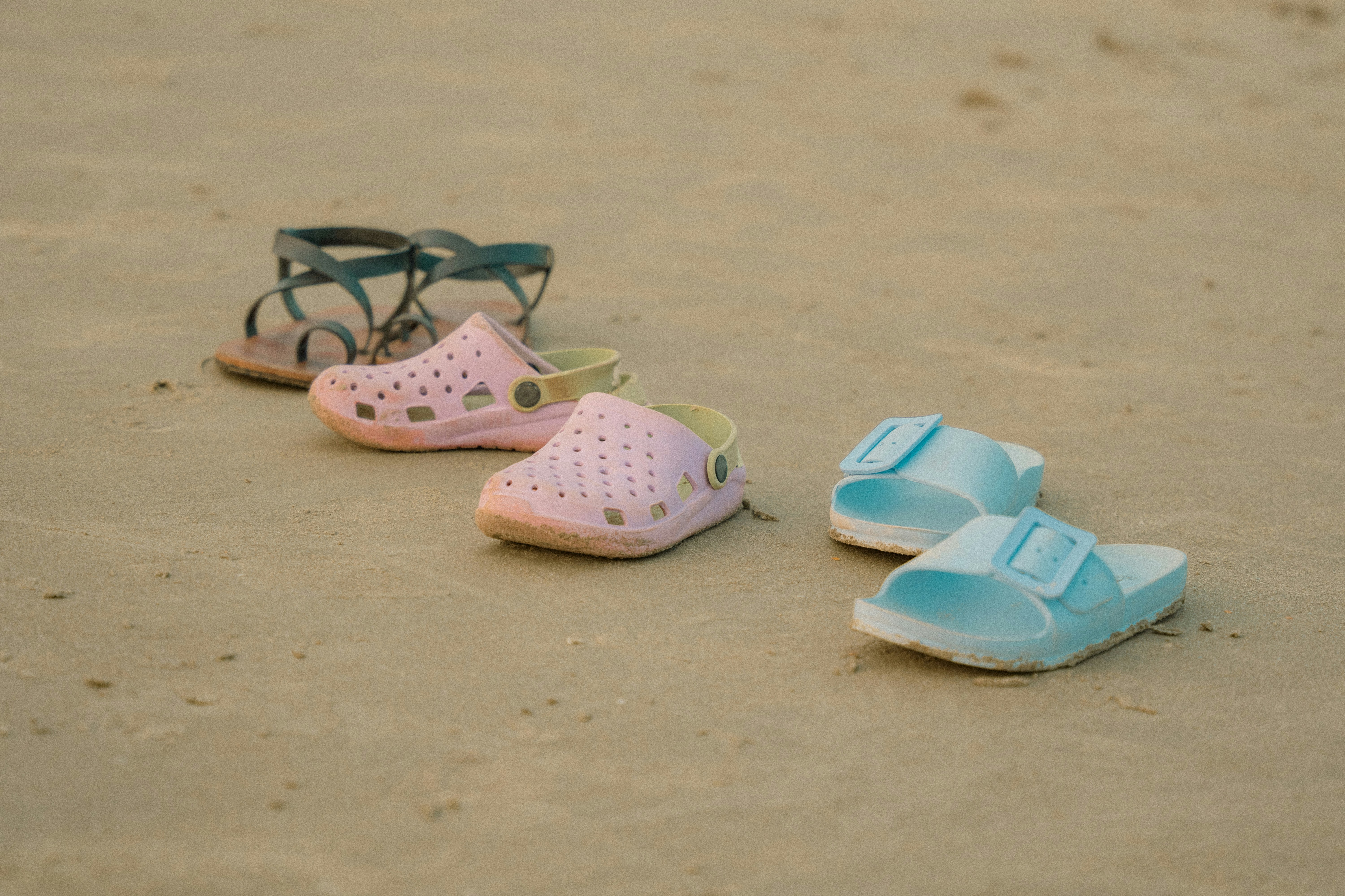 Three pairs of shoes sitting on a beach