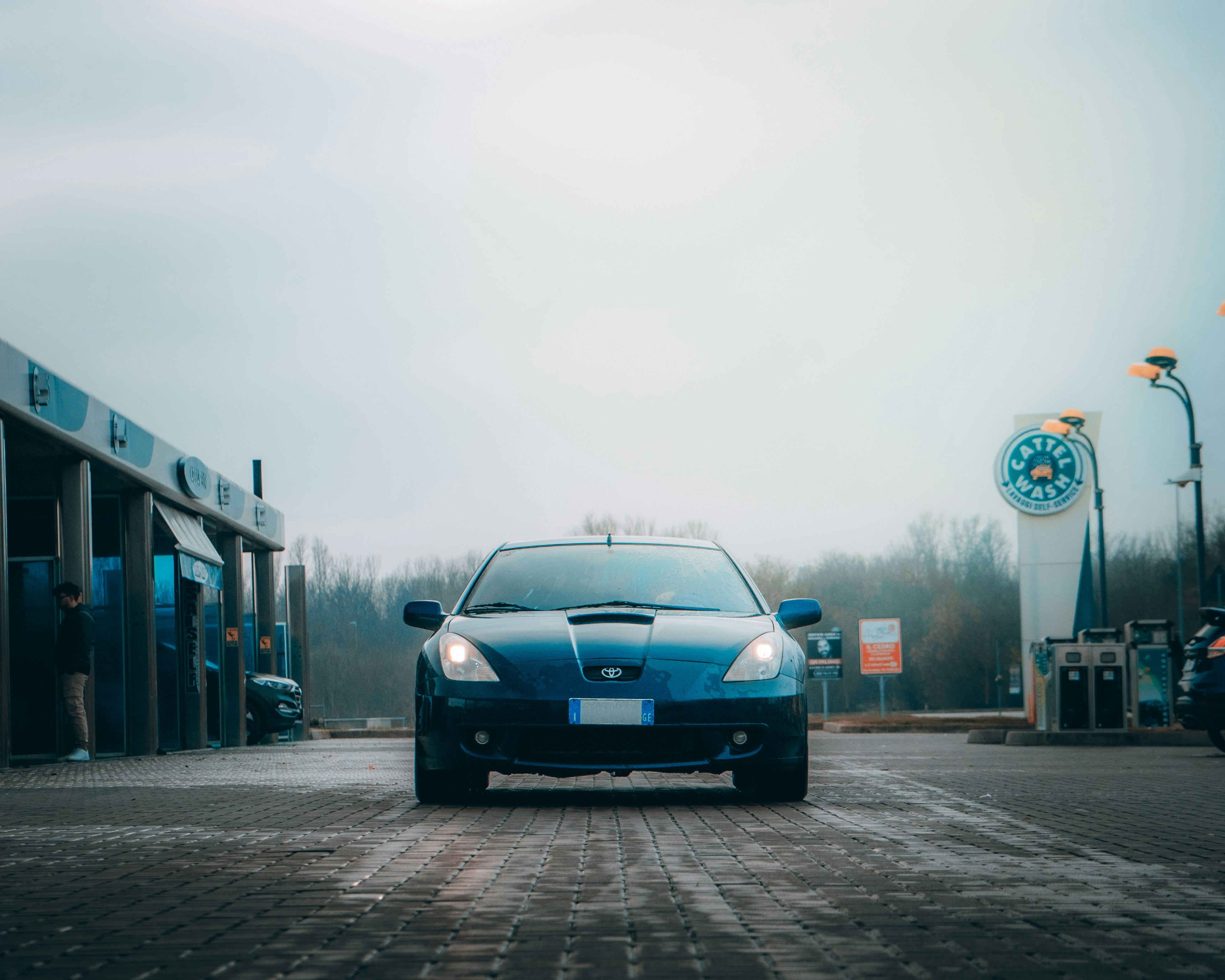 A blue car parked in front of a gas station