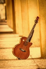 A guitar sitting on the ground next to a wall