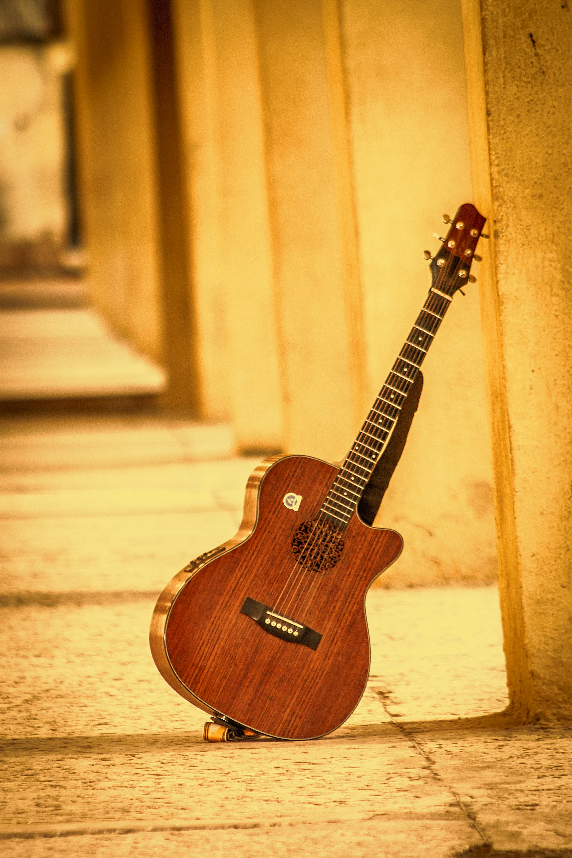 A guitar sitting on the ground next to a wall