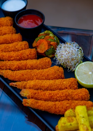 A platter of fried food with a side of dipping sauces