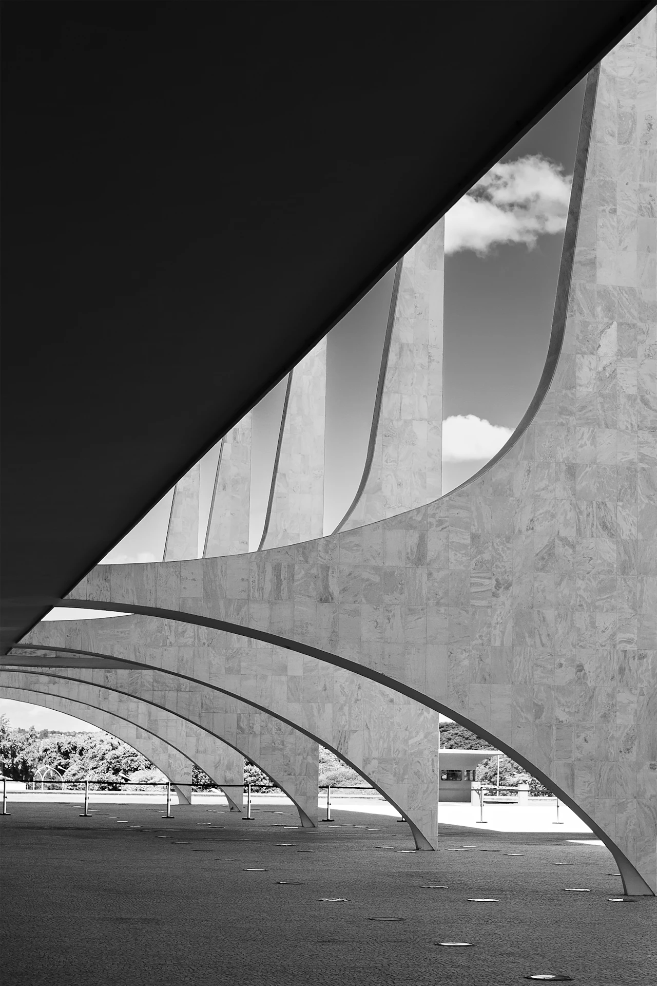Arcos de mármore de Oscar Niemeyer em Brasília, sob a sombra diagonal da cobertura.