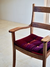 A wooden chair with a purple cushion on it