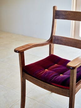 A wooden chair with a purple cushion on it