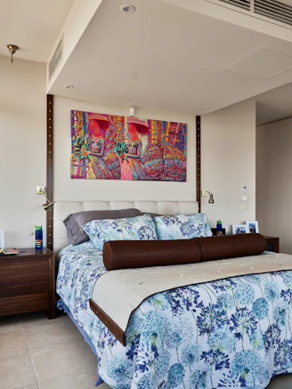 A bedroom with a large bed and a painting on the wall