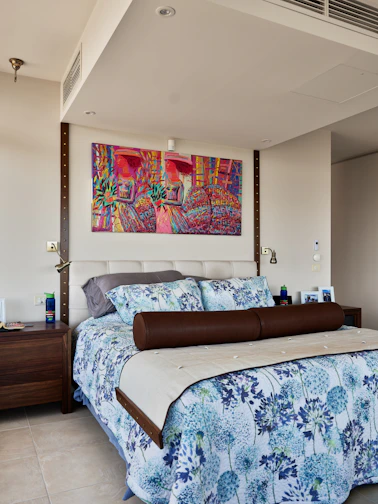 A bedroom with a large bed and a painting on the wall