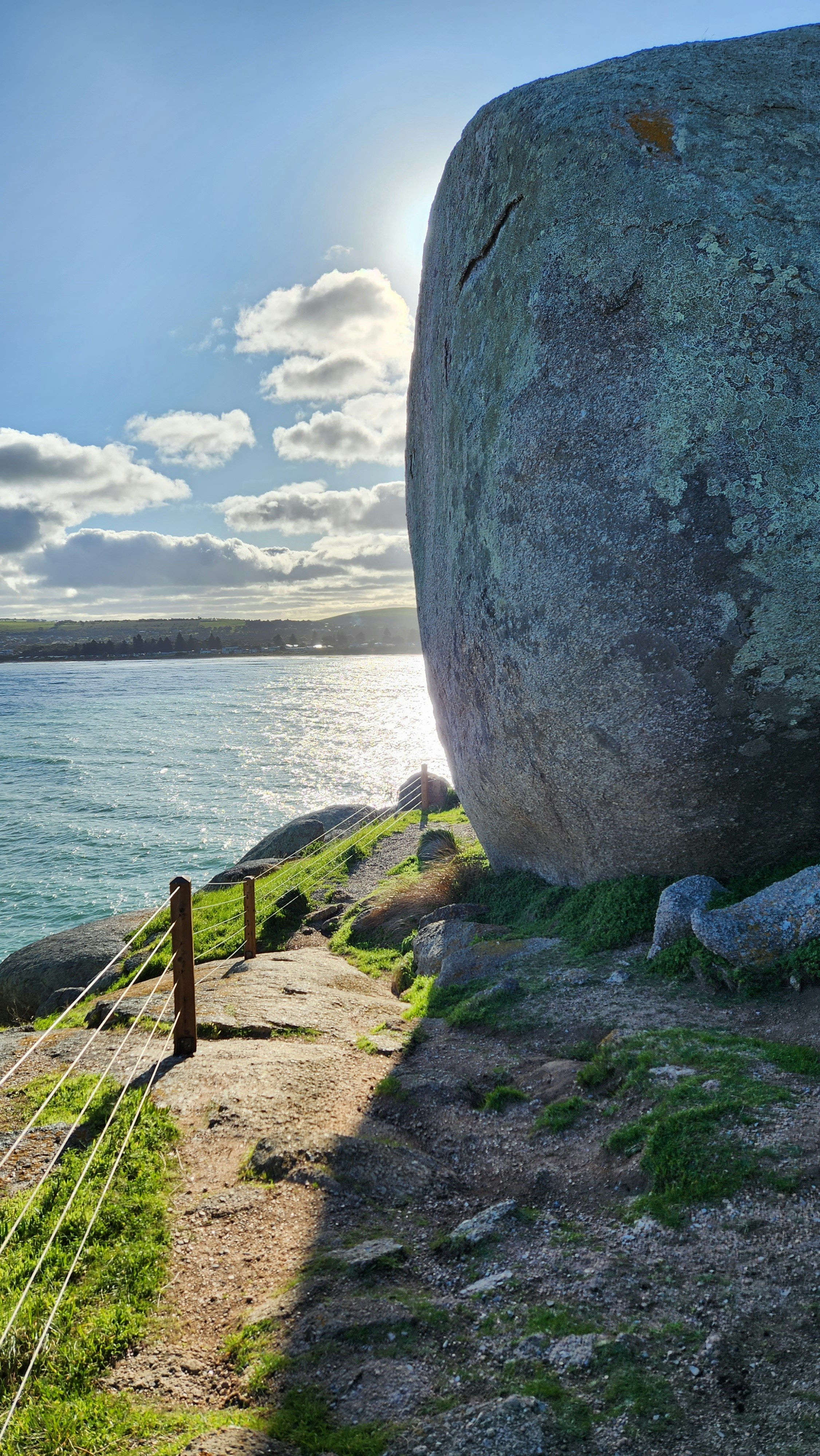 A large rock sitting on top of a lush green hillside
