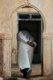 A man in a white robe walking out of a doorway