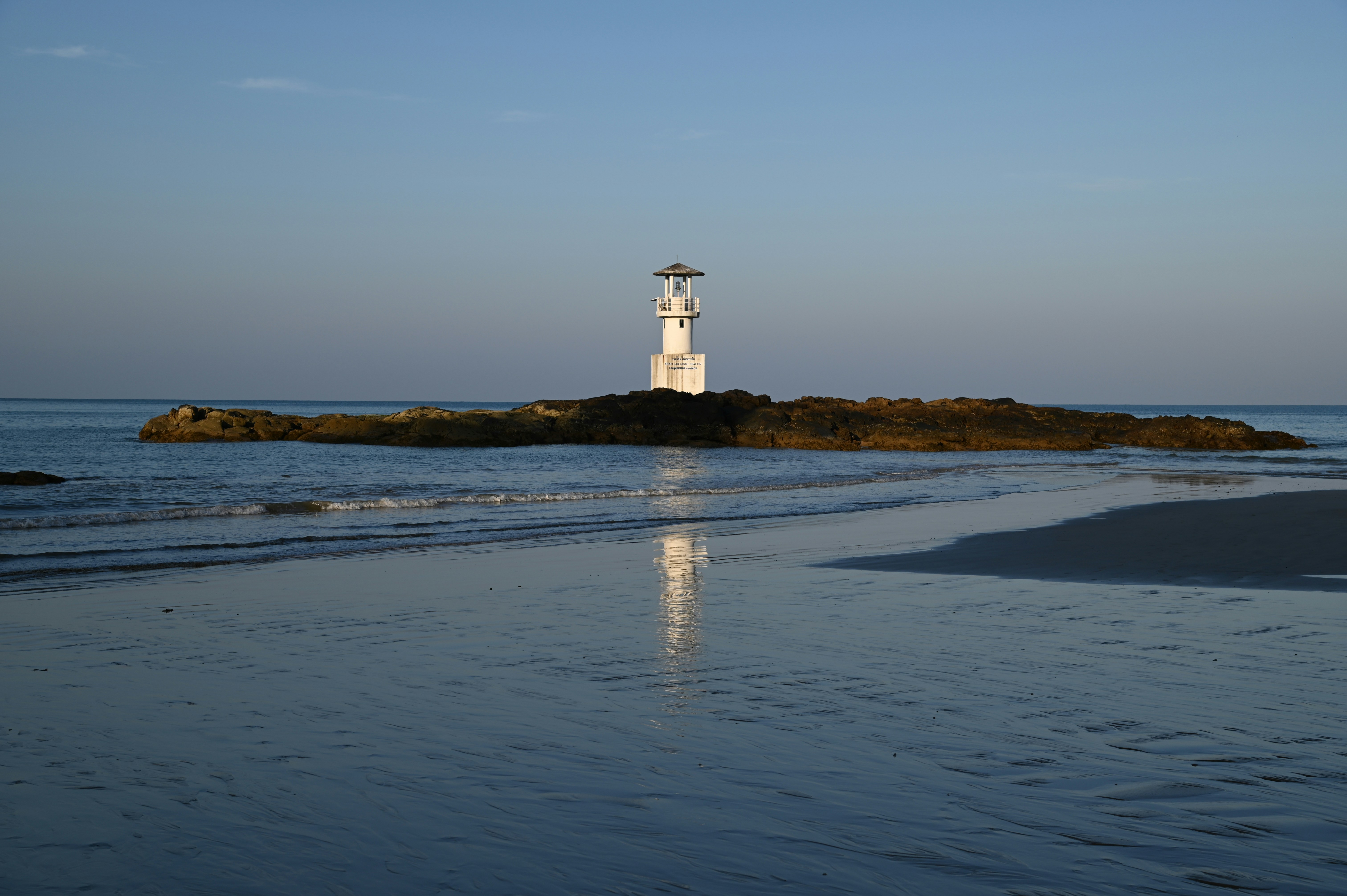 A white light house sitting on top of a small island
