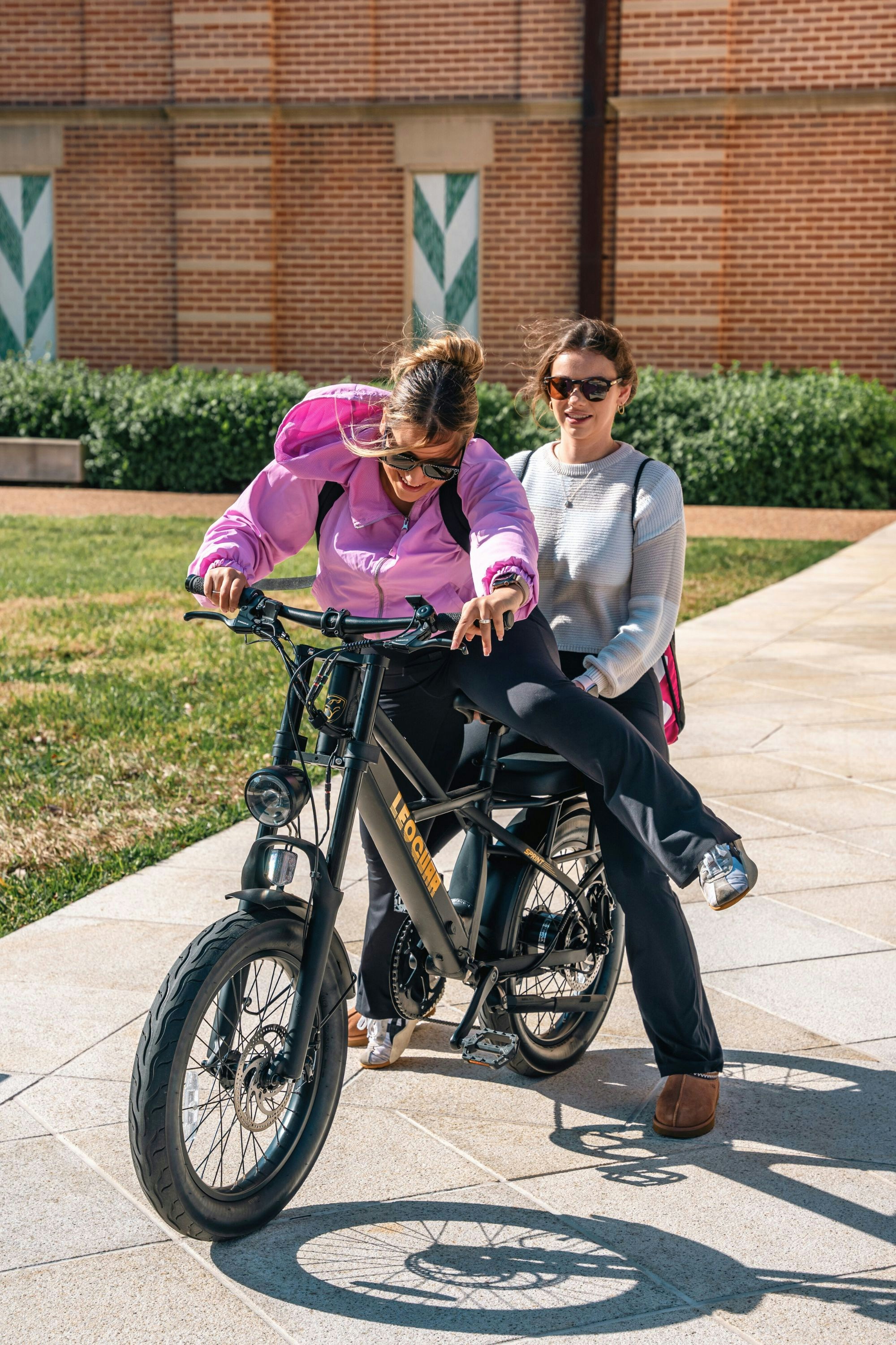 A woman sitting on a bike next to another woman