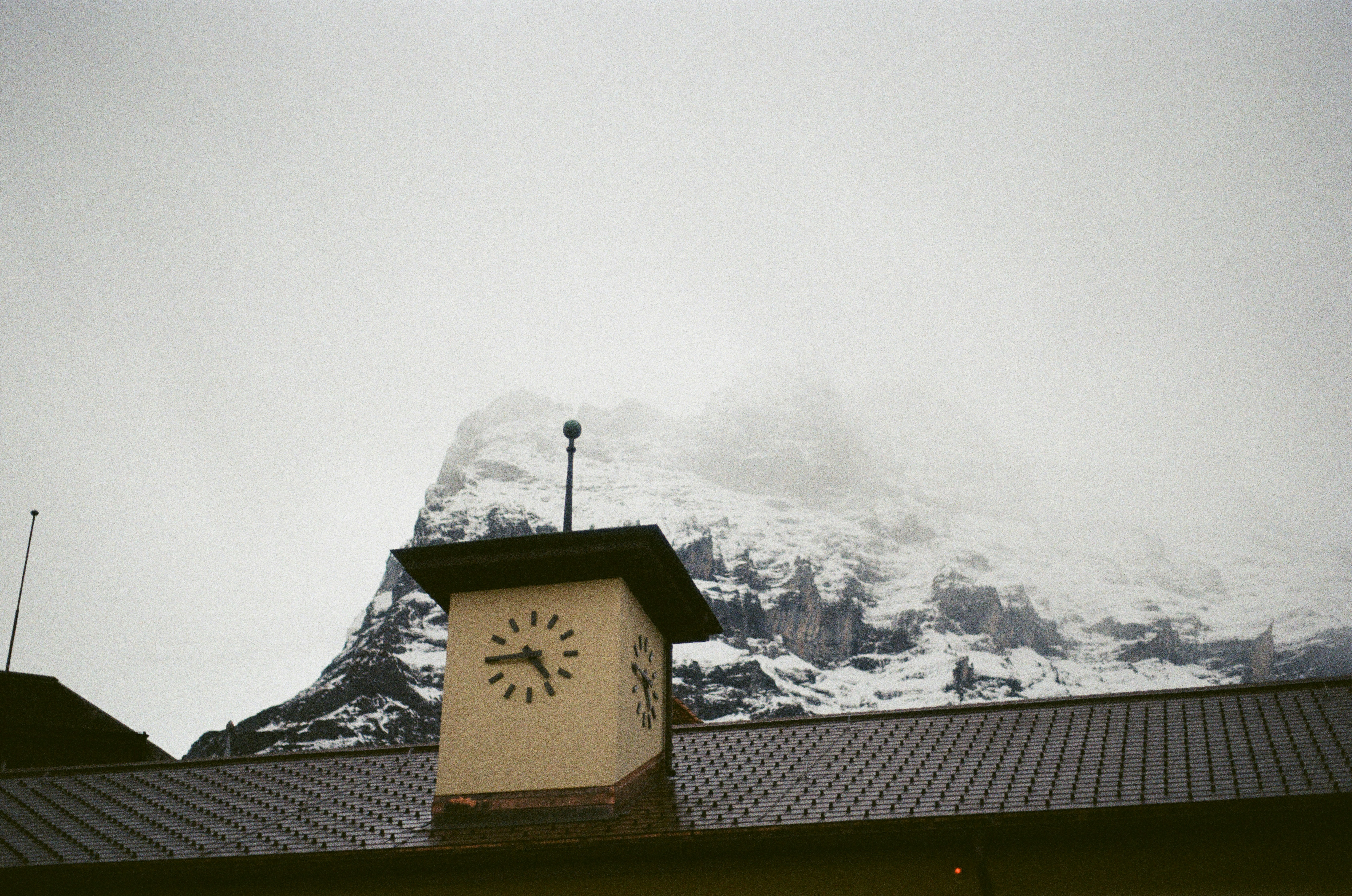 Une horloge sur le côté d’un bâtiment avec une montagne en arrière-plan