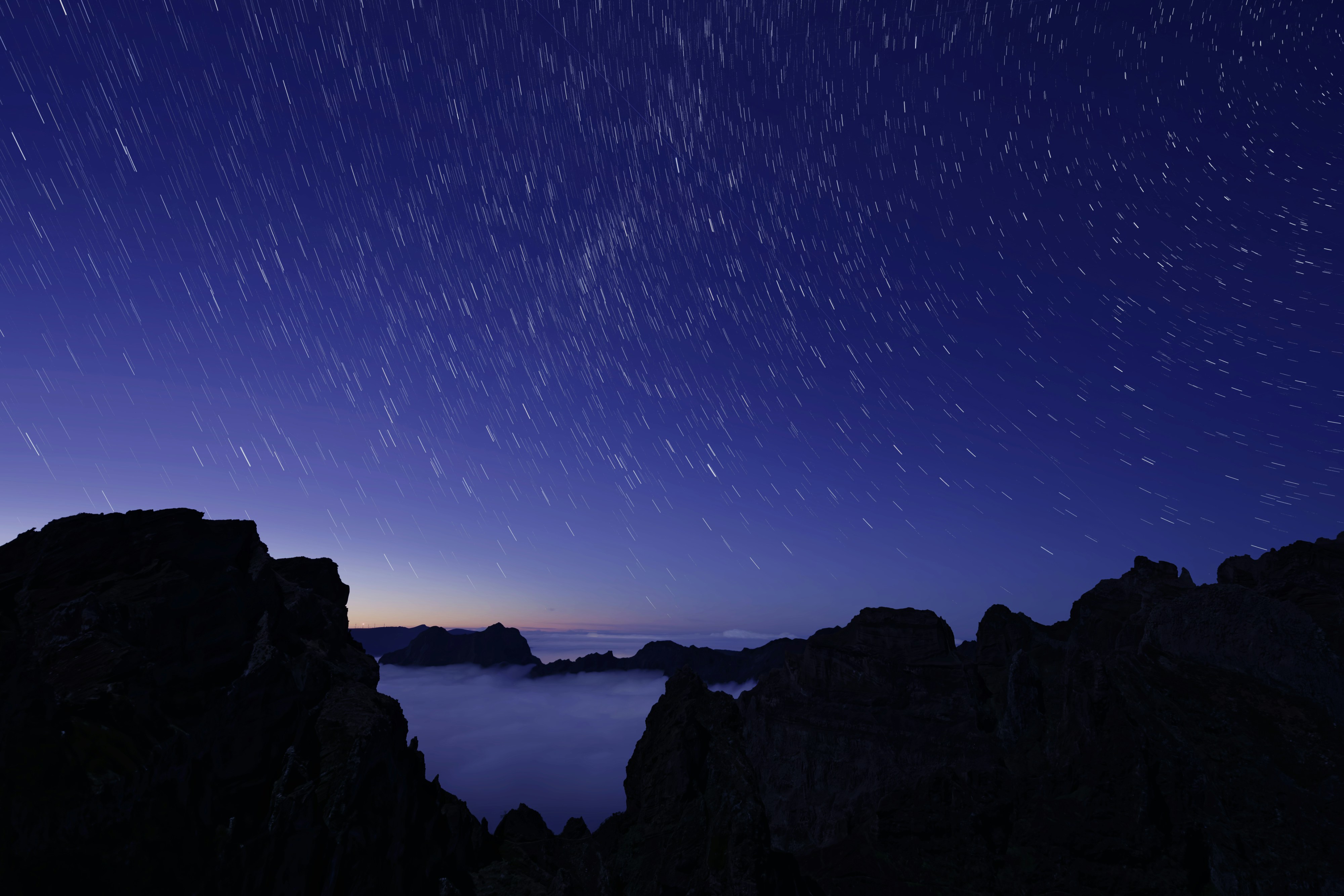 The night sky is full of stars above the mountains