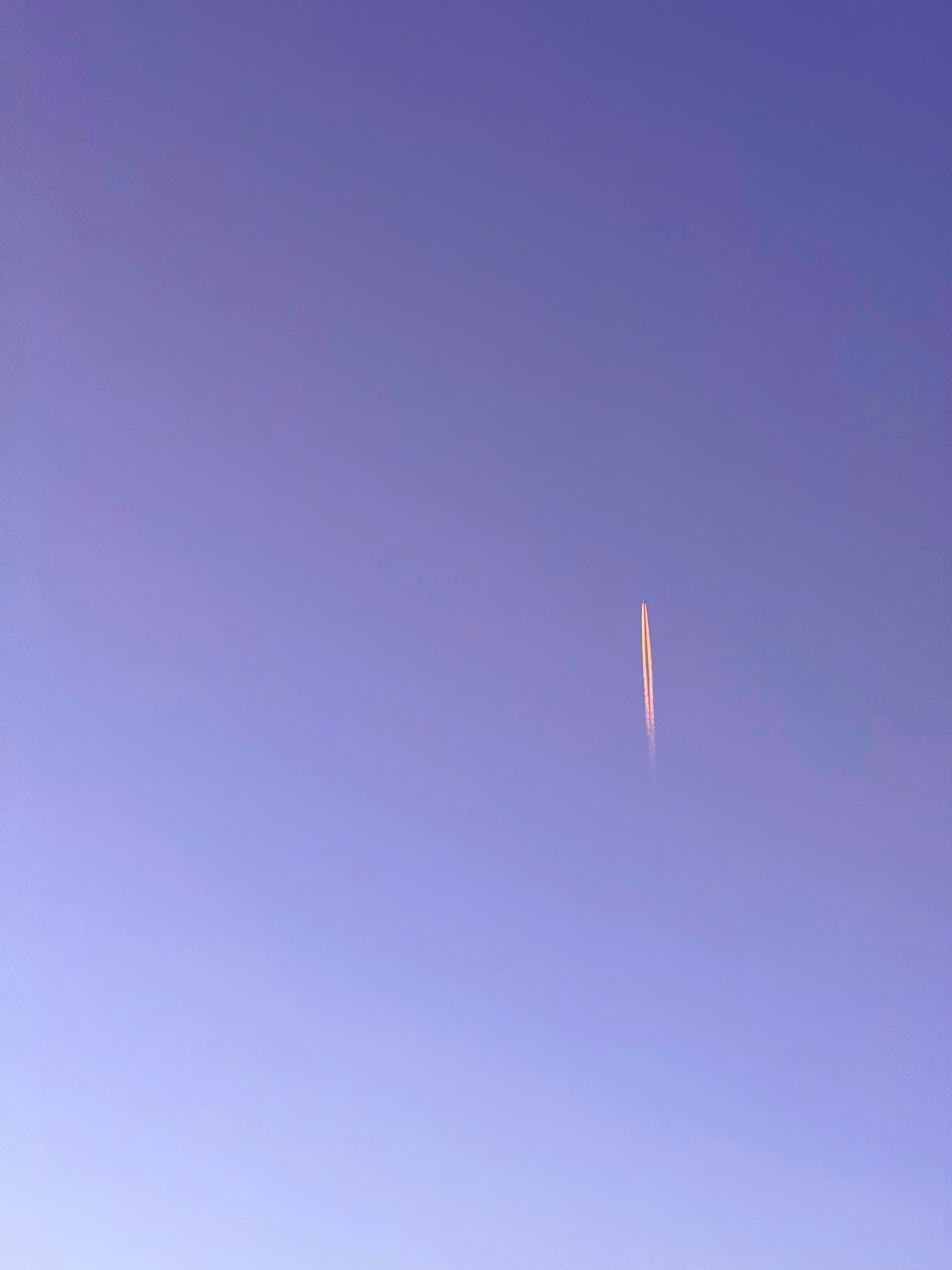 A jet flying through a blue sky next to a tall building