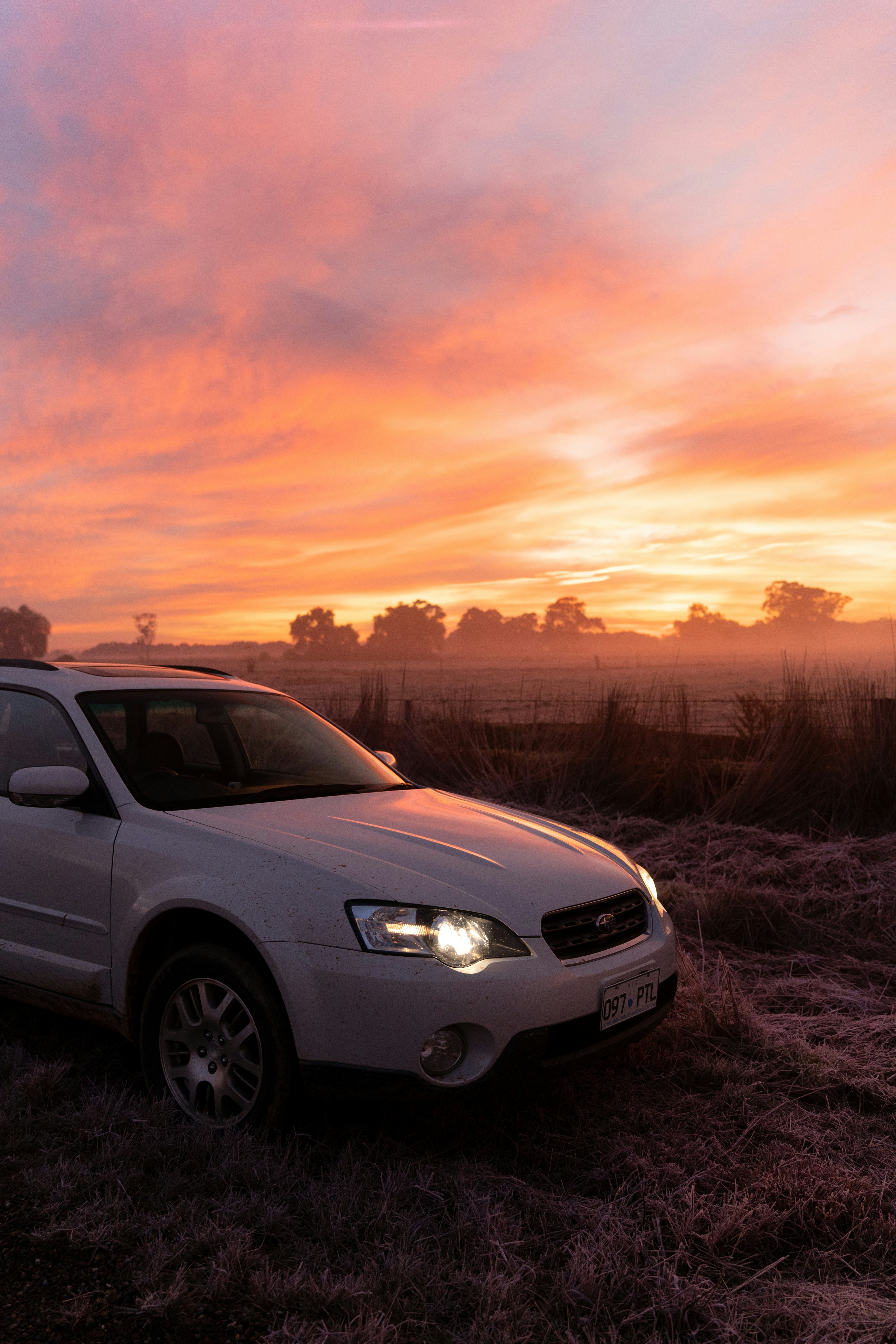 A car parked in a field at sunset
