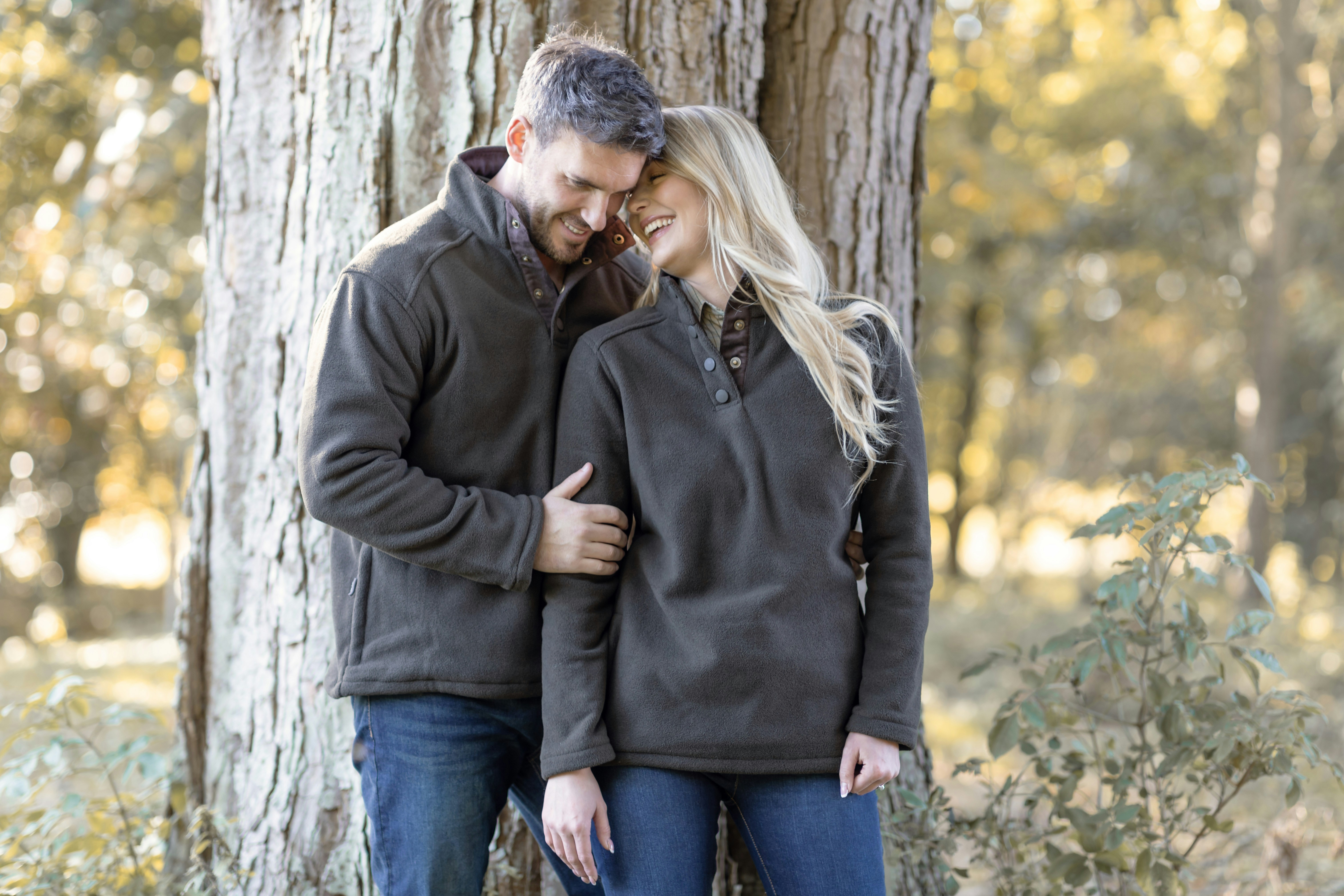 A man and woman standing next to each other in front of a tree