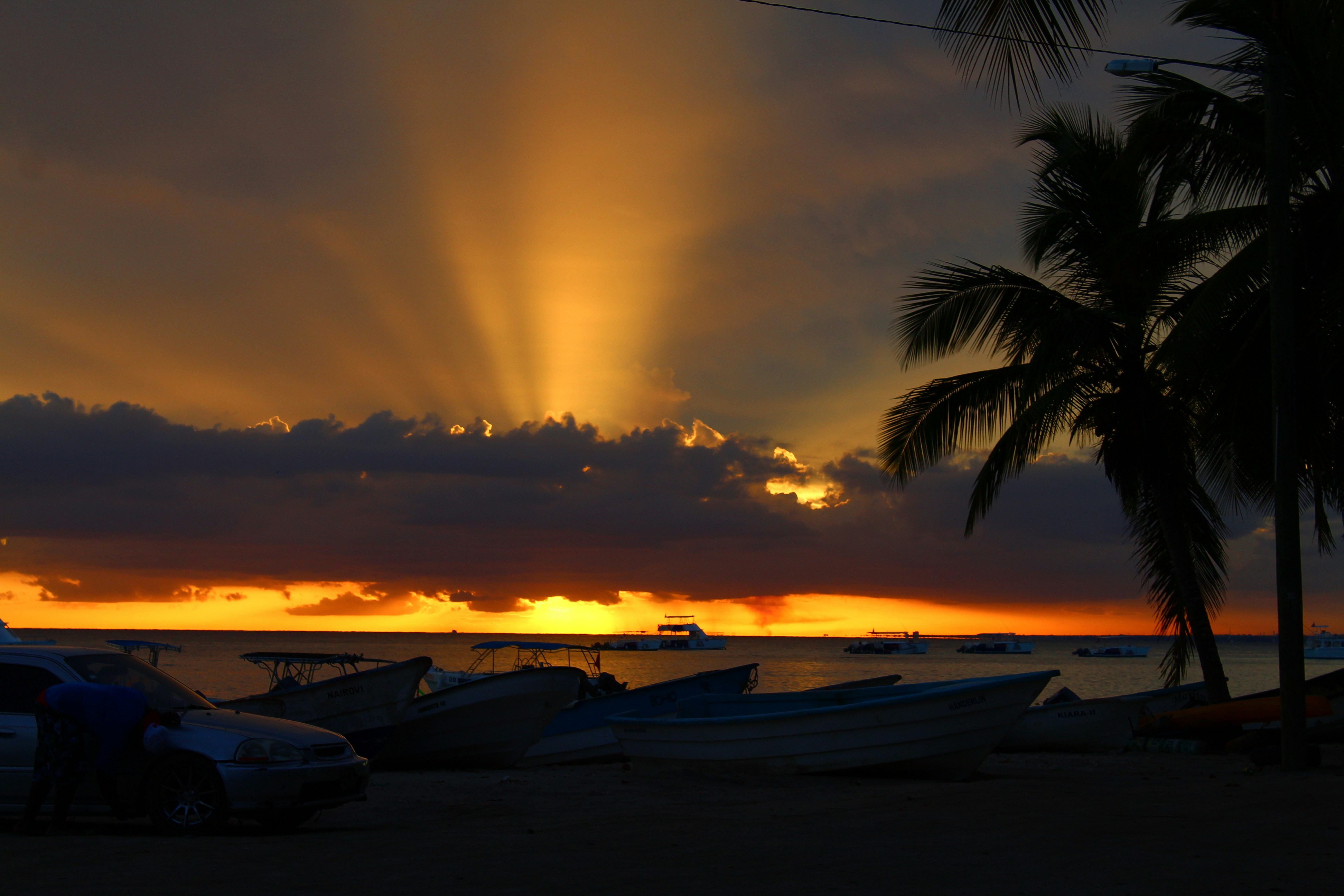 A sunset over a beach with boats parked on the shore
