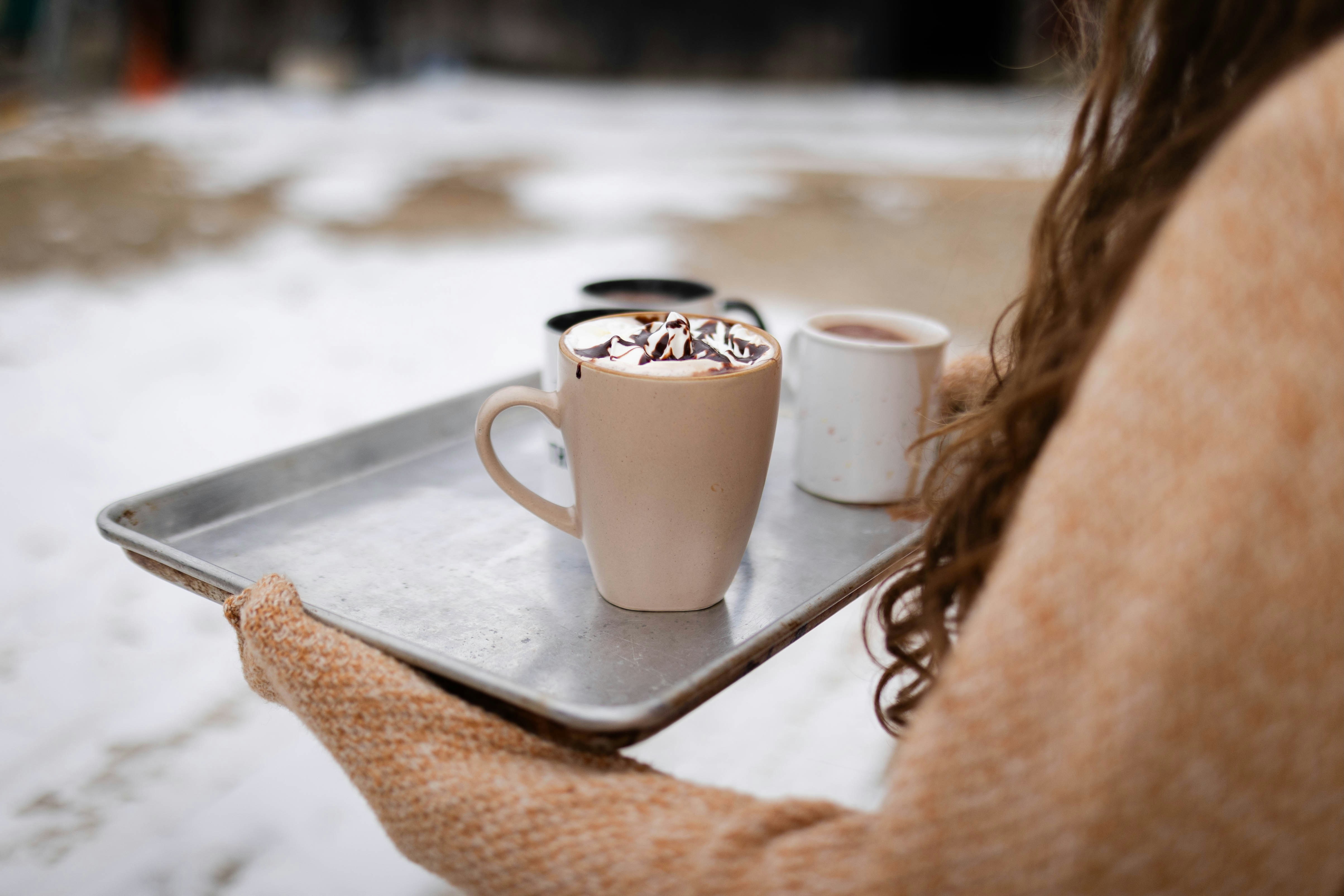 A woman holding a tray with two cups of coffee