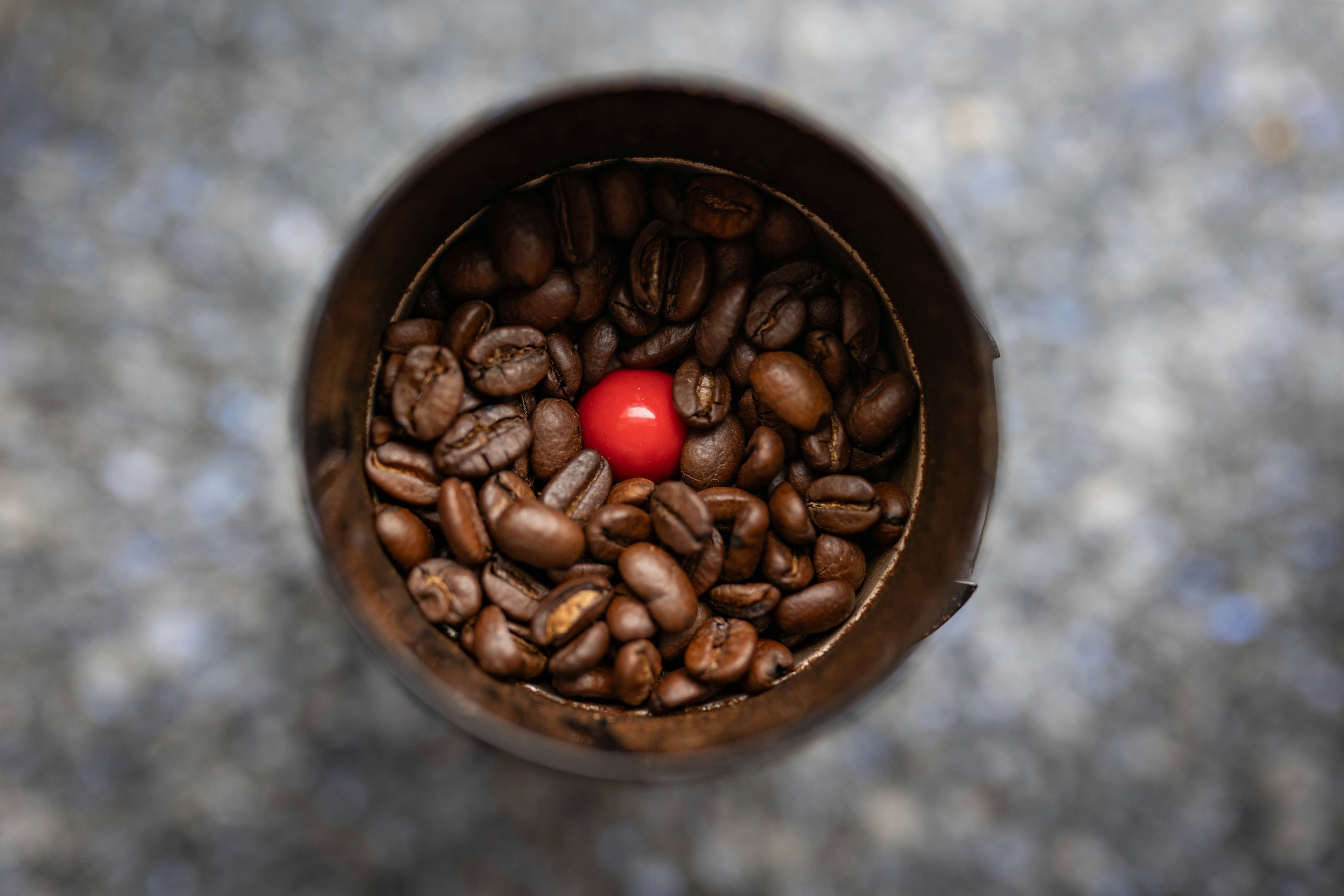 A cup filled with coffee beans and a red ball