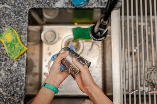 A person is cleaning a sink with a rag