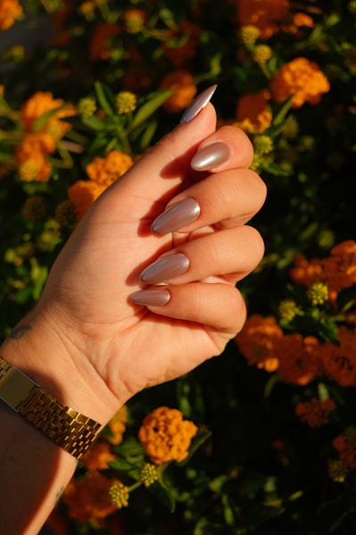 A woman's hand with a manicure holding a flower
