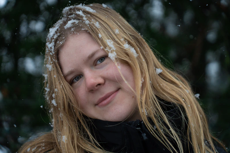 Frau steht im Schnee mit wehenden Haaren