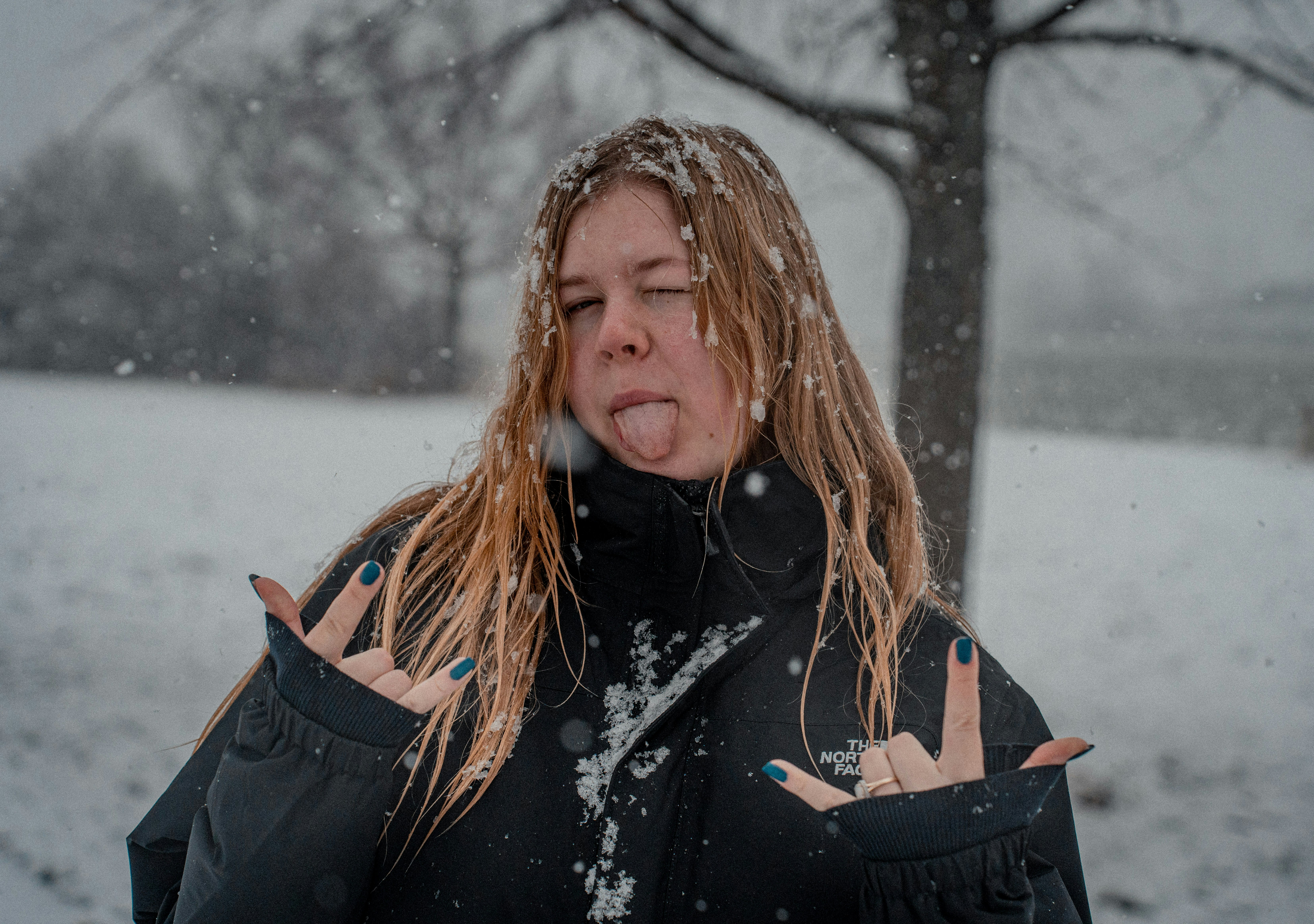 A woman standing in the snow blowing her hair