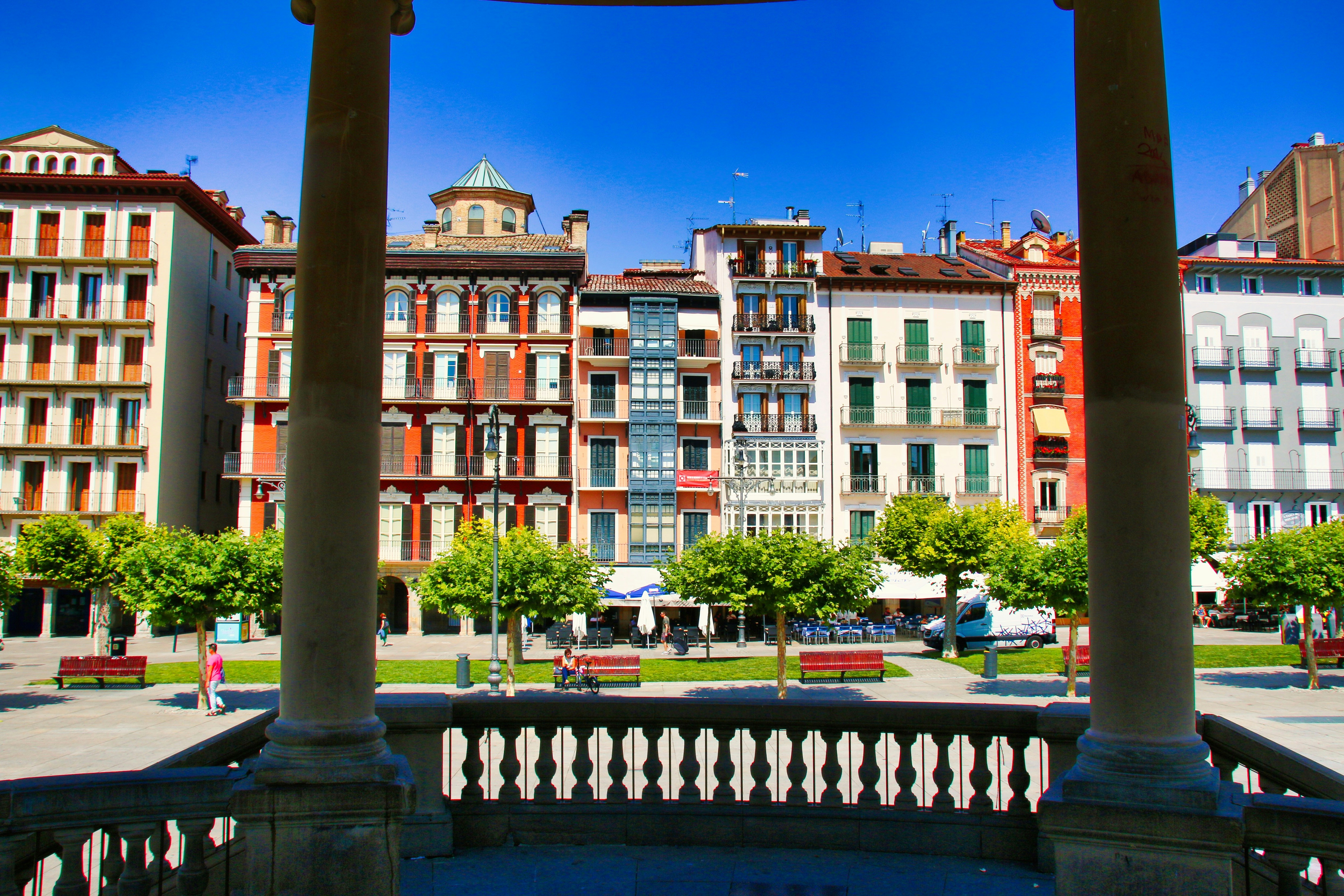A clock on a pole in front of some buildings