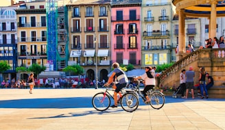 A couple of people riding bikes down a street