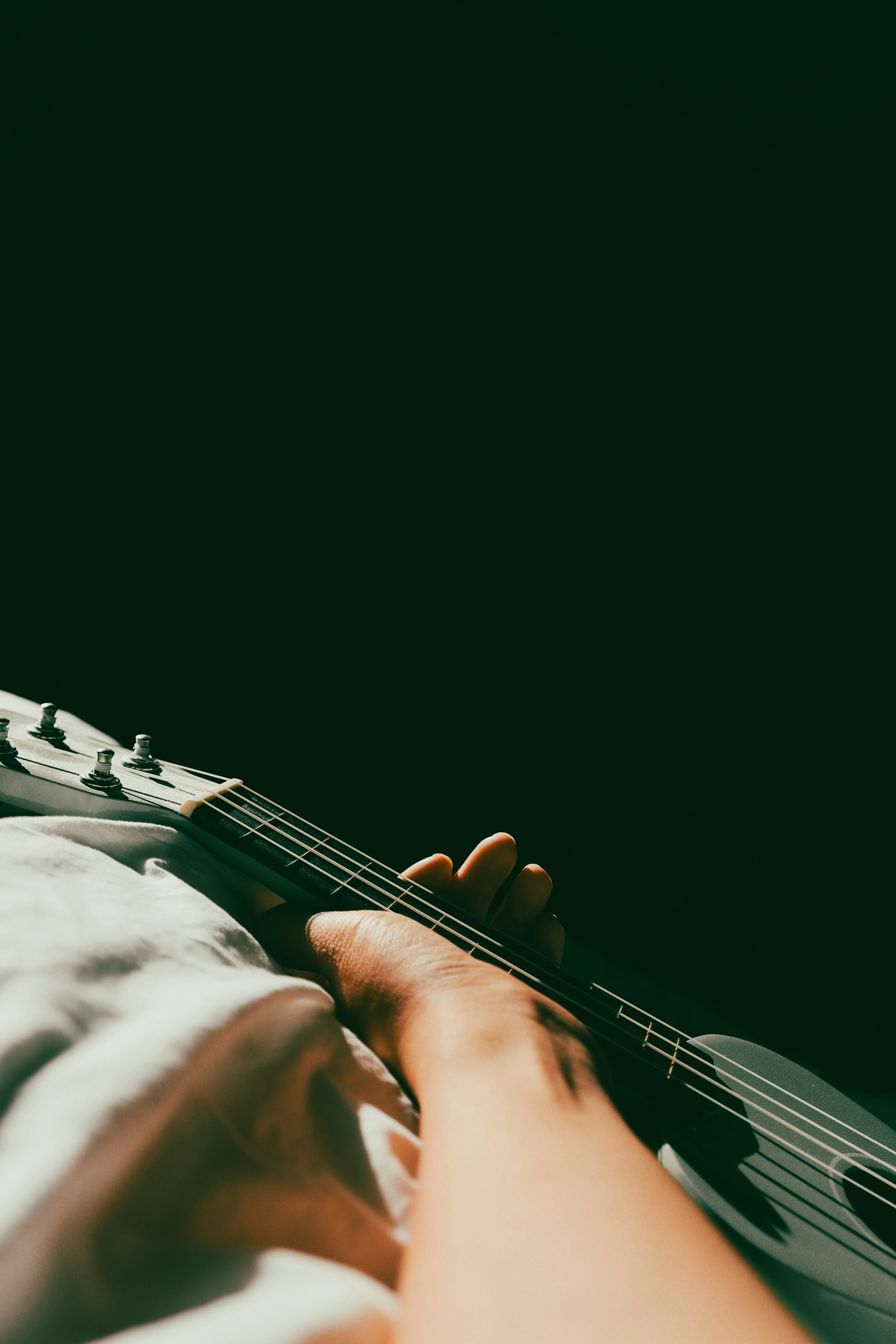 A person laying on a bed with a guitar