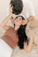 A woman laying on the beach with a man