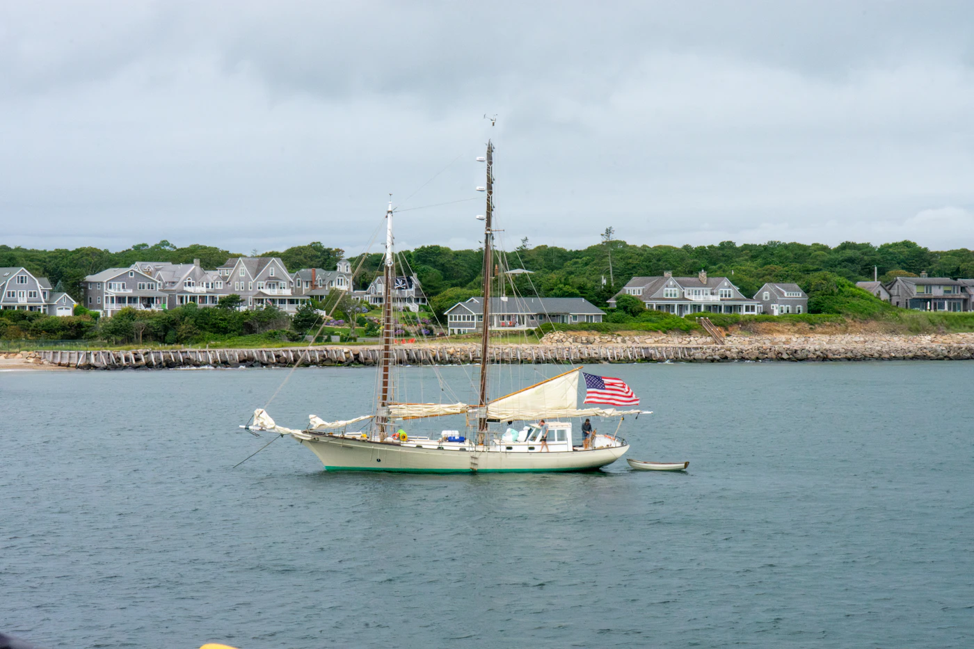 A sailboat moored off a shingled North Shore shoreline on a calm morning