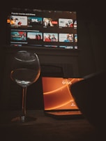 A glass of wine sitting next to a laptop computer